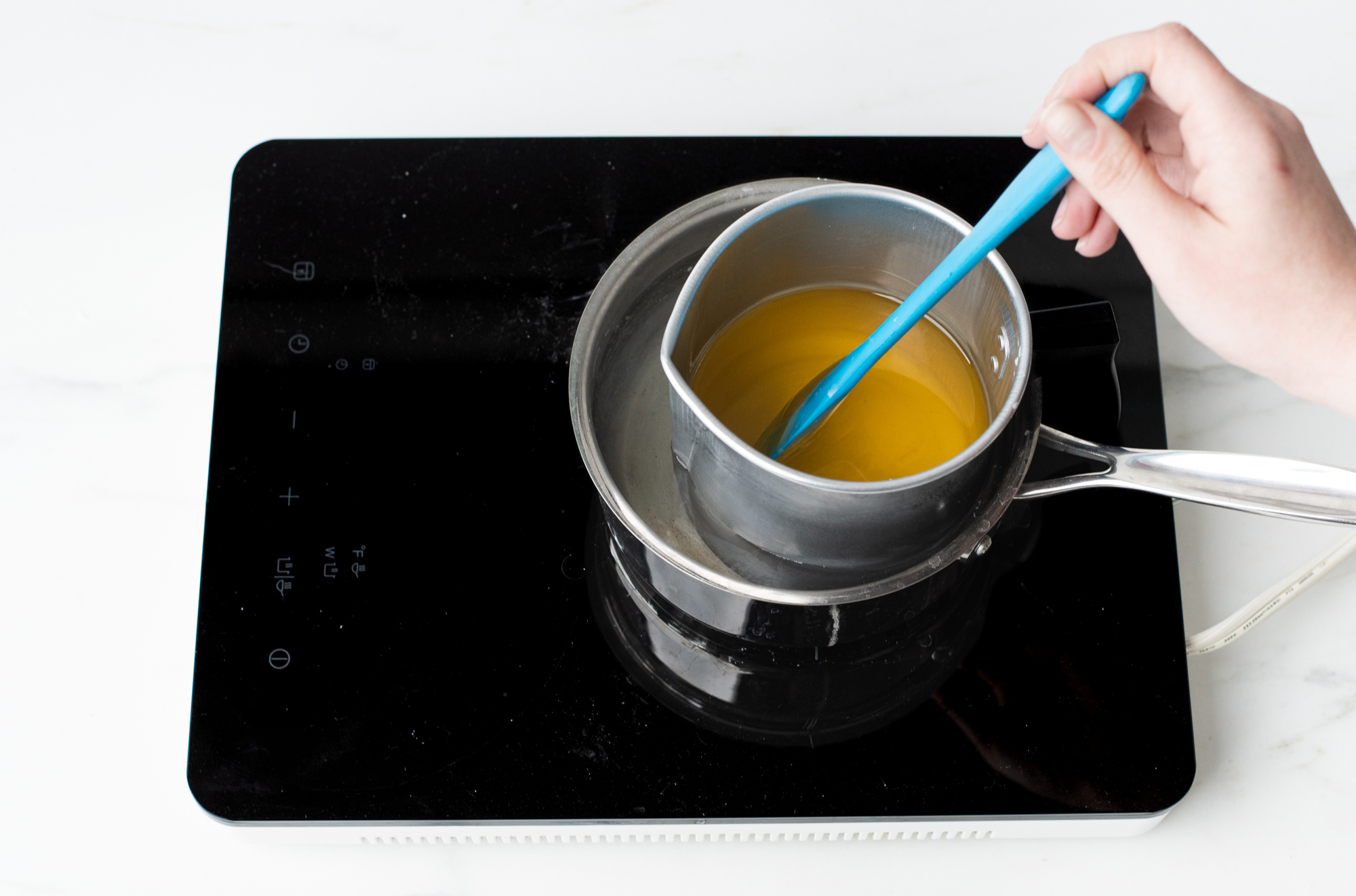 Stirring melted wax with a spatula.