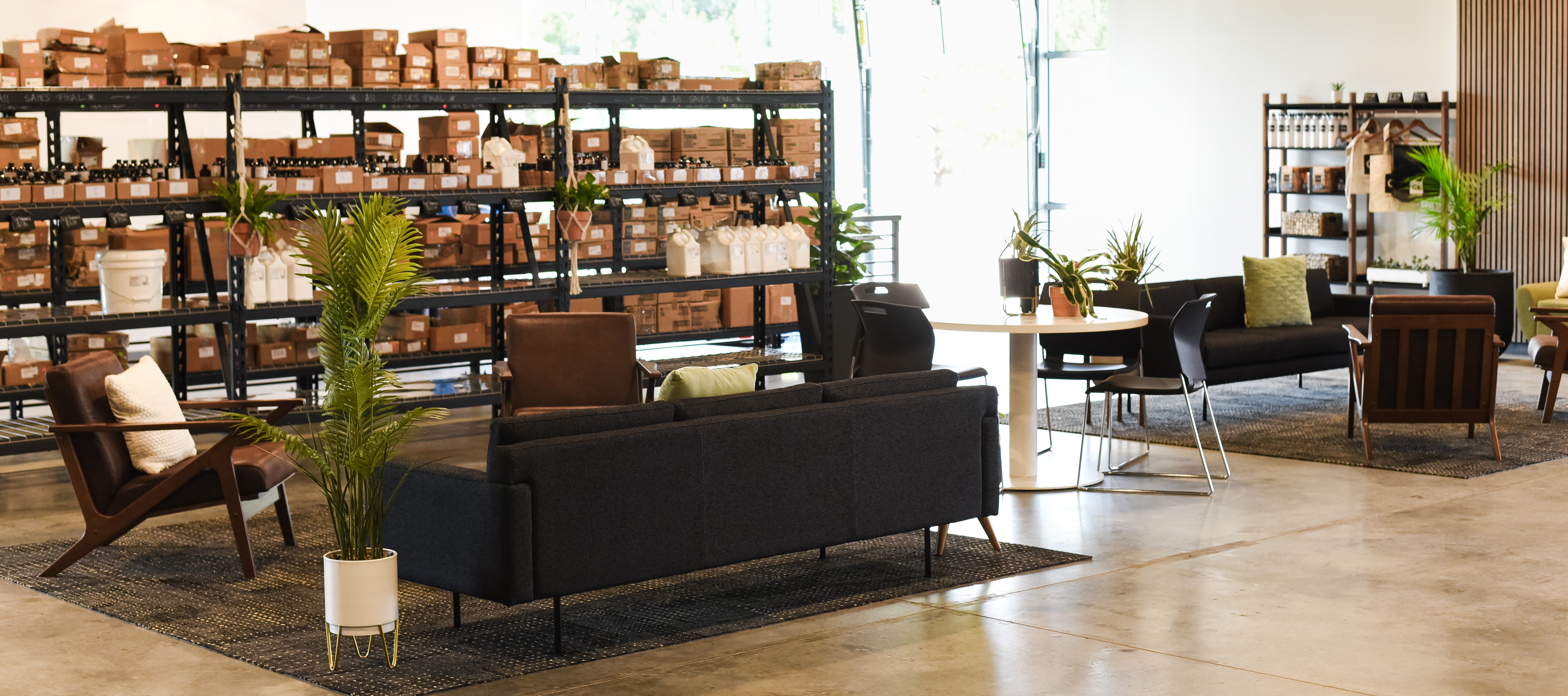 An area of a store with a couch for lounging while waiting for pickup orders. Racks with assorted clearance items are nearby the couch. 