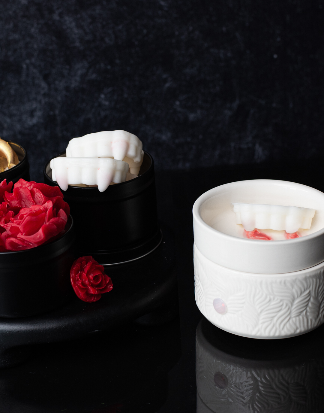 Wax melts in the shape or red roses and white vampire teeth. The vampire teeth reveal red mica swirls as they melt.