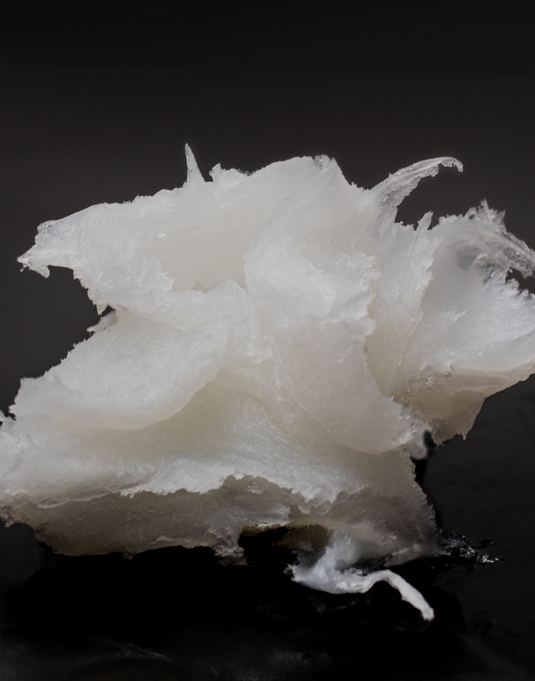 Up-close shot of soft paraffin wax. The wax is white and slightly transparent with a thick jelly-like texture.