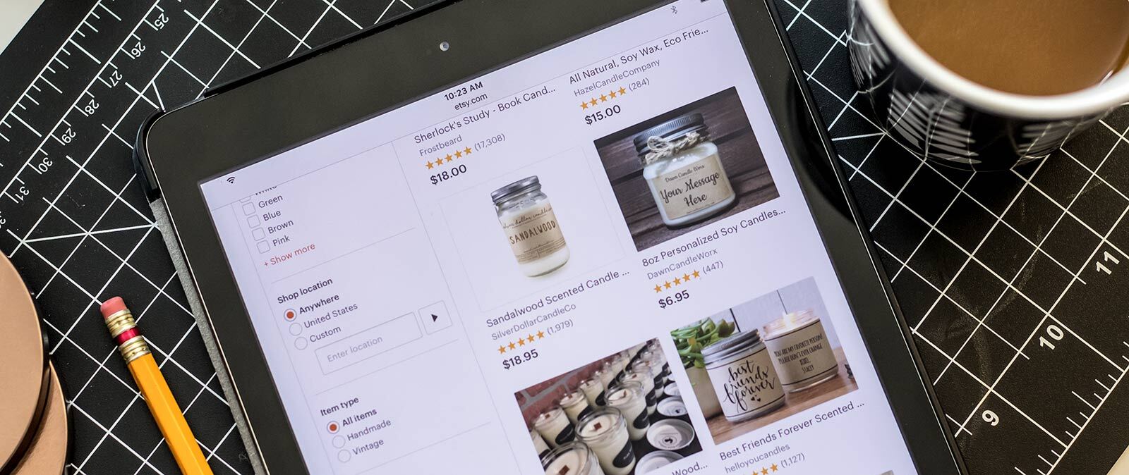 A tablet on a tabletop displays the Etsy website and candles for sale