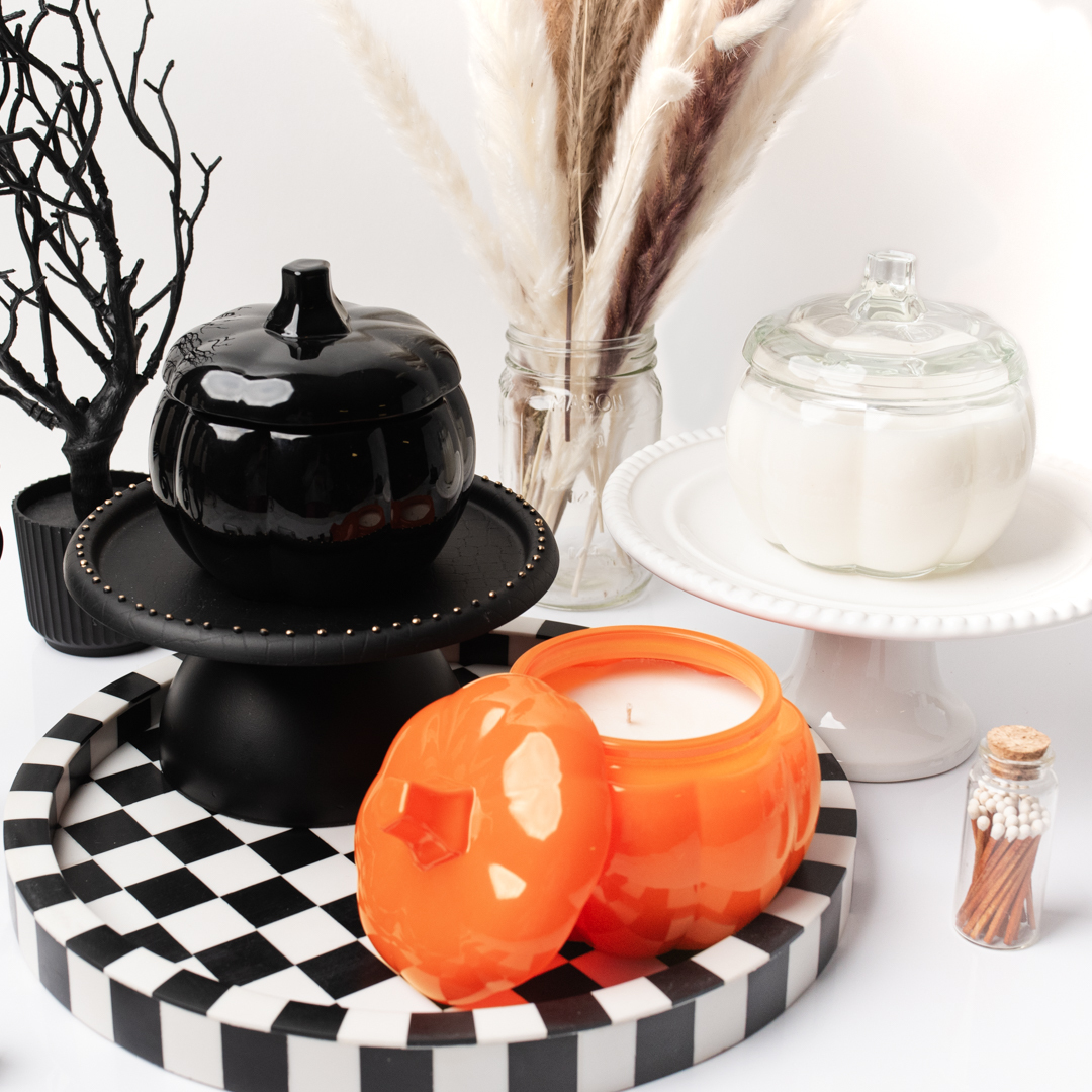 A black, orange, and clear pumpkin container on a black and white checker platform.