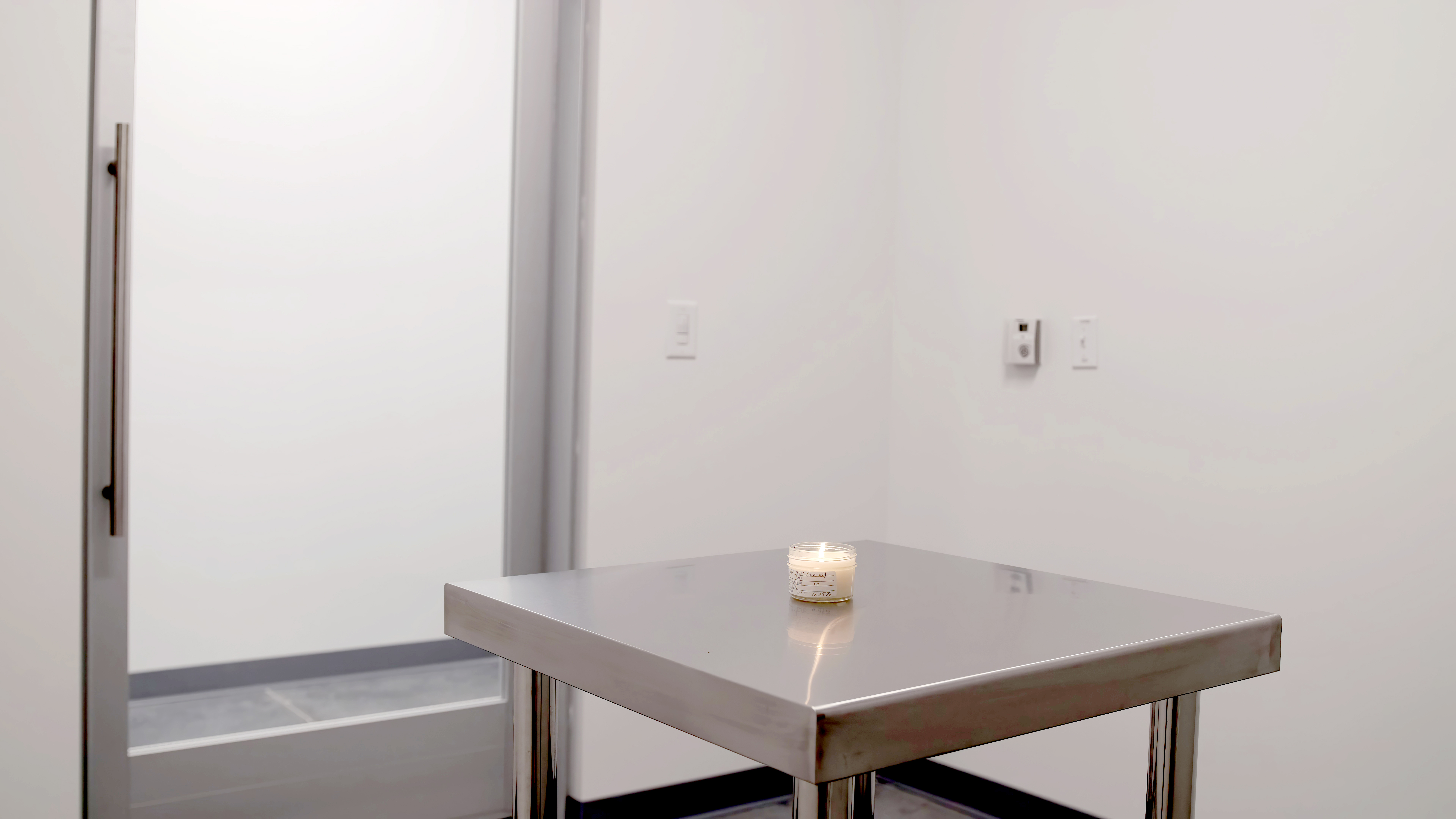 A burning test candle sits on a stainless steel table in a fragrance booth at CandleScience.