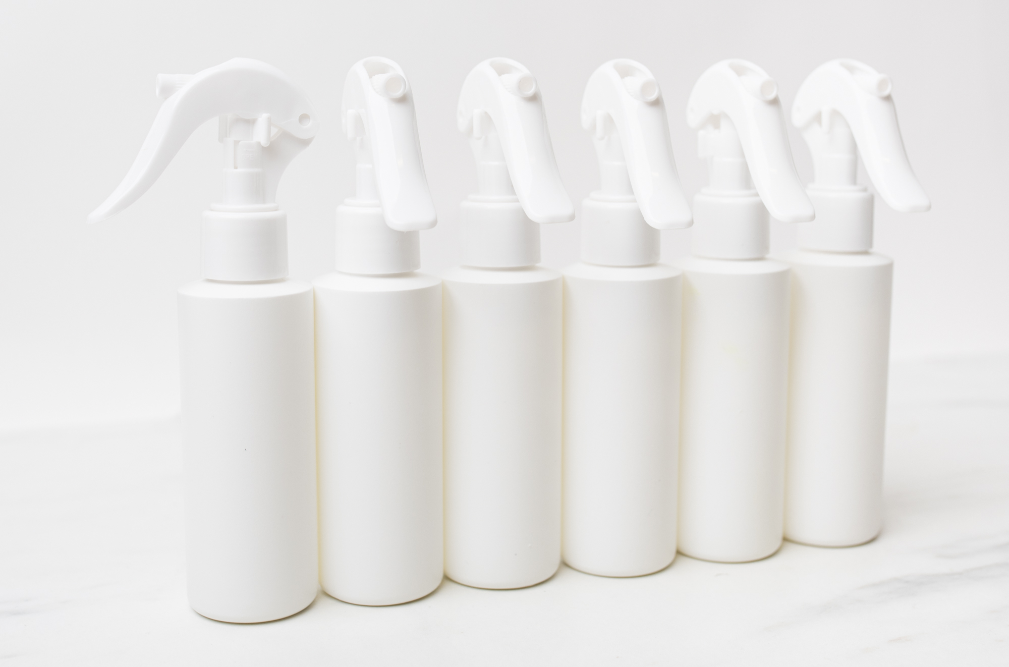 Six white spray bottles in a row.