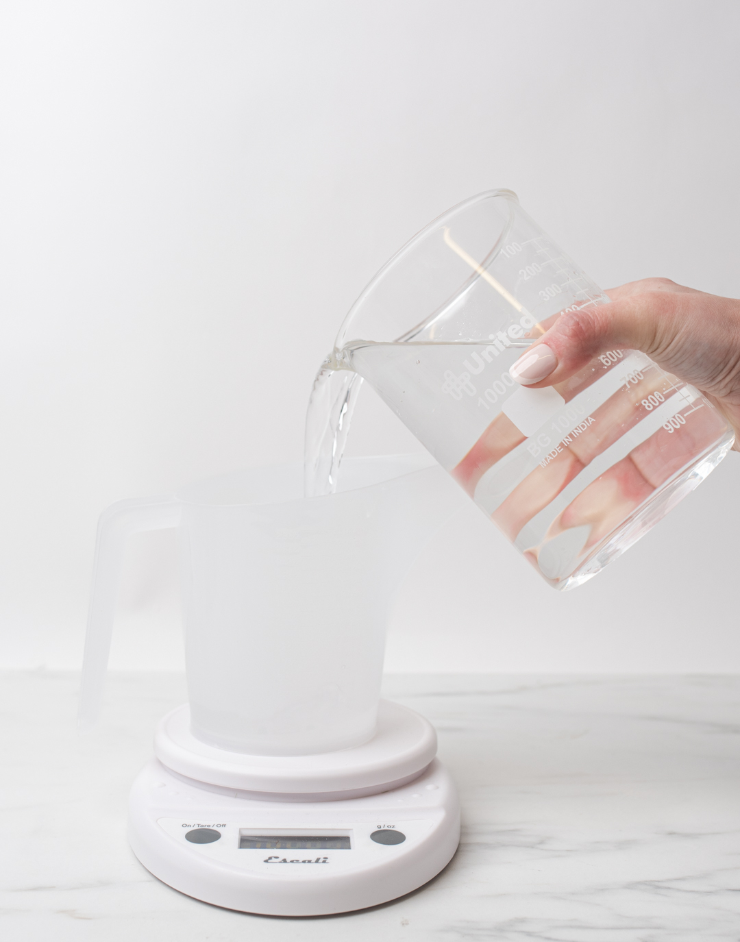 Pouring water into pouring pitcher on scale. 