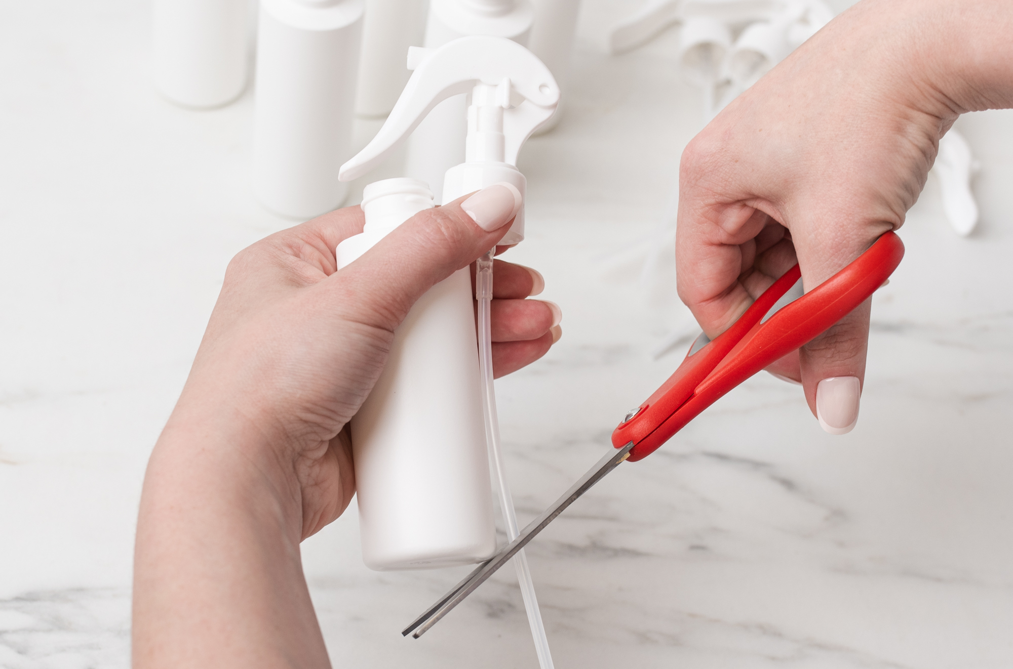 Using scissors to cut sprayer dip tube to the proper length for bottle.