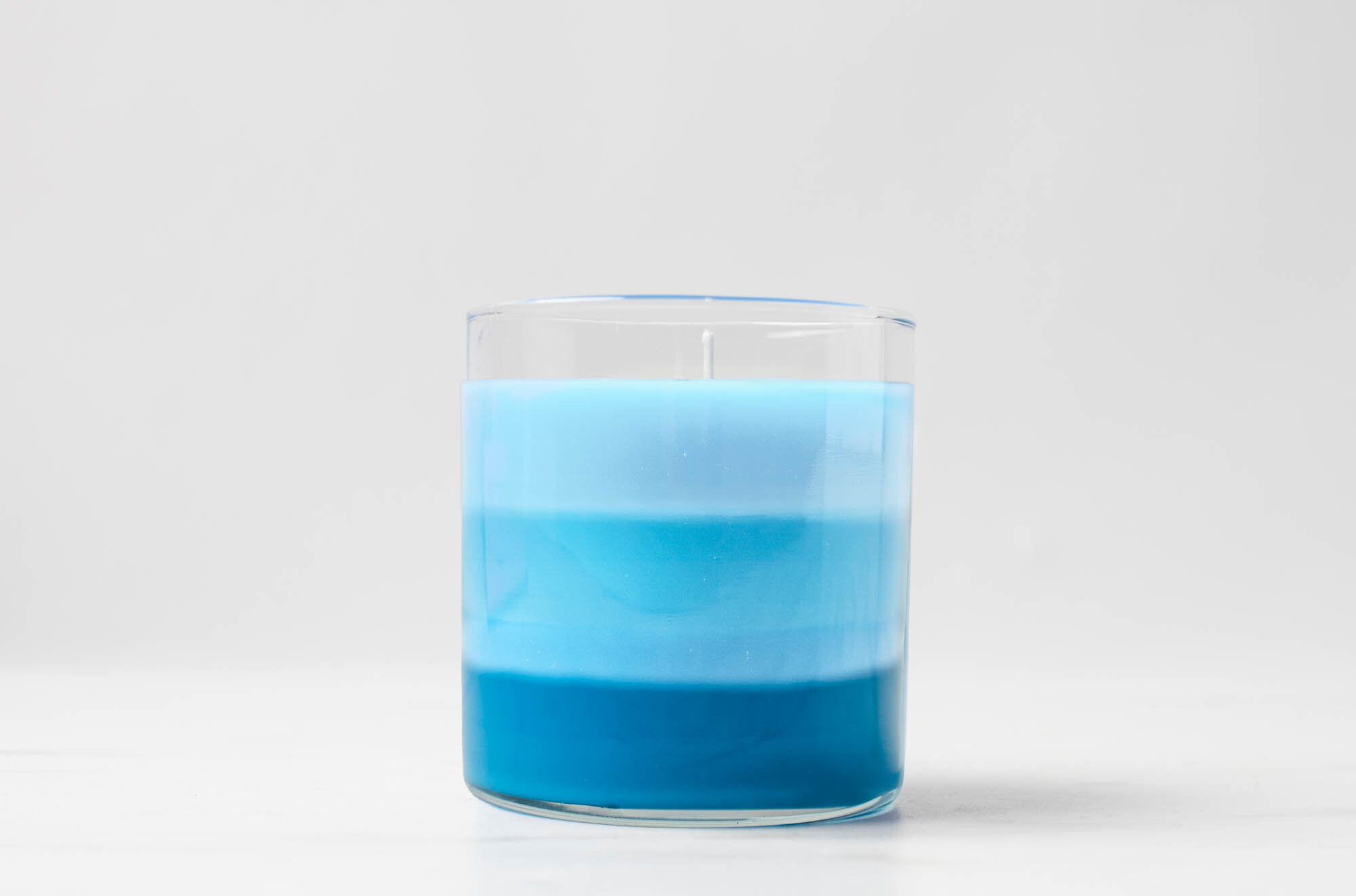 Layered scented candle with ombre blue colors.