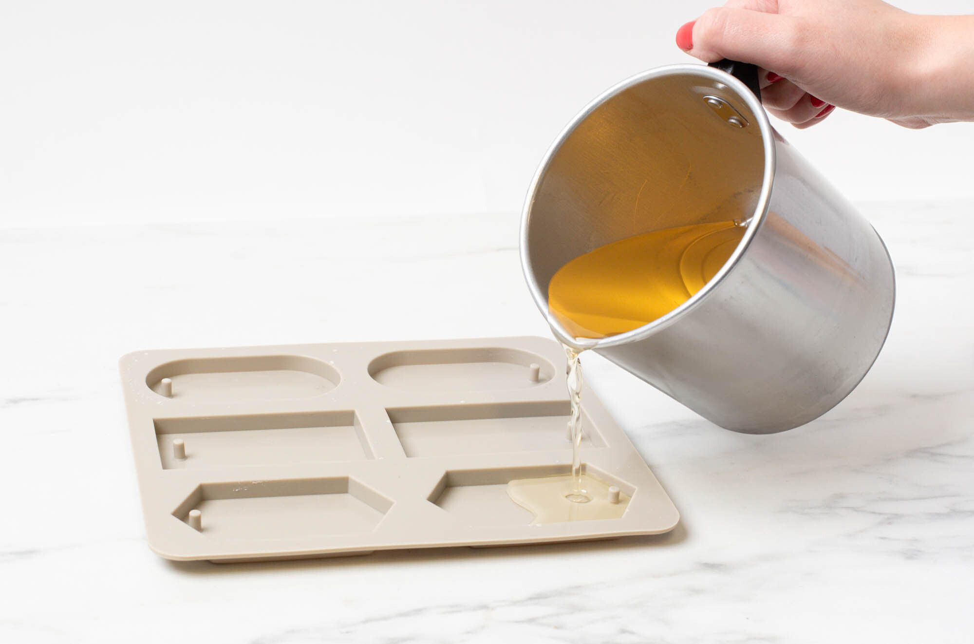 Pouring melted wax into a silicone mold.