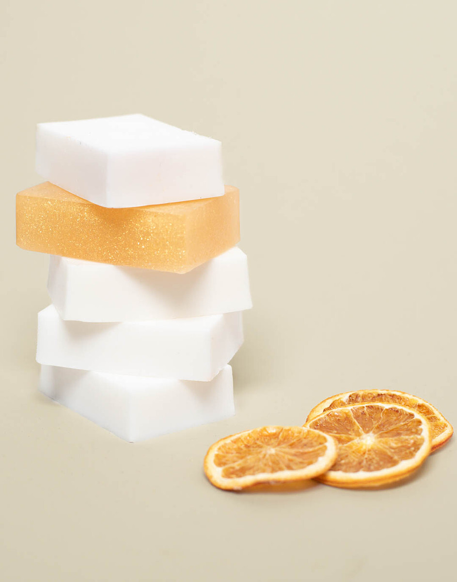 Five bars of melt and pour soap are stacked vertically next to orange slices.