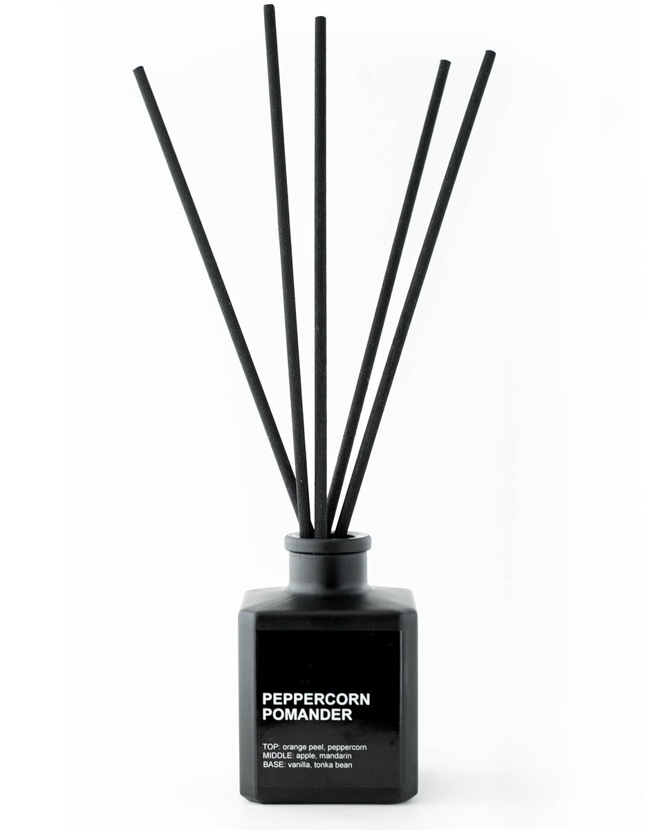 A matte black reed diffuser bottle with black reed diffuser sticks against a white background.