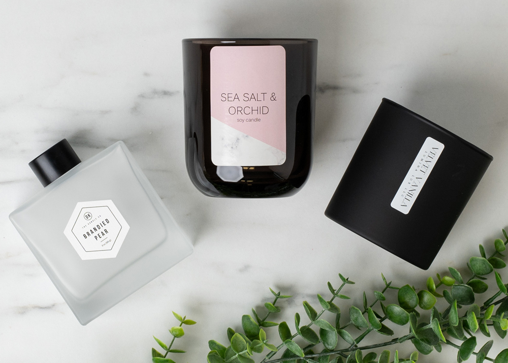 Matte Black Tumbler Jar, Smoke Sonoma and Frosted Square Reed Diffuser Bottle on white marble table with greenery