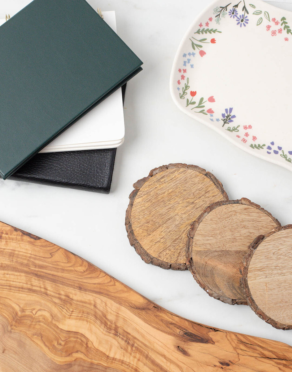 Stone coasters, a ceramic tray with flower details, and wood slices that can be used as props in candle and soap product photos