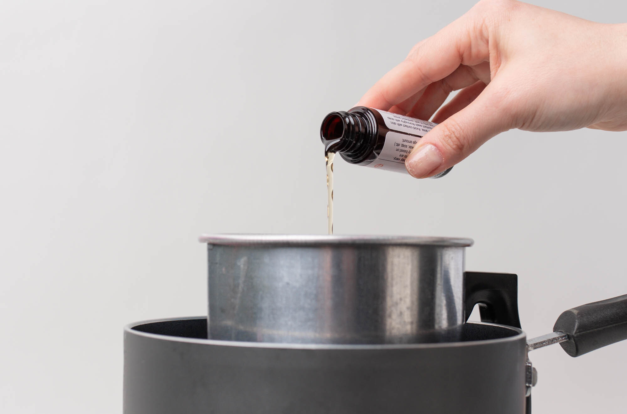 Pouring fragrance oil into melted soy wax.