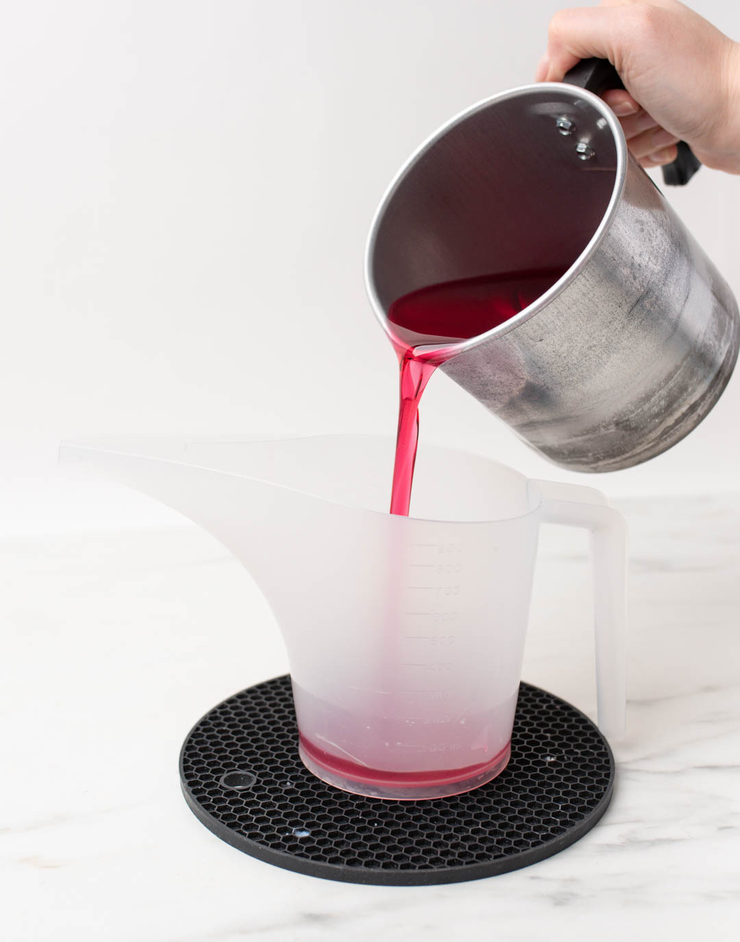 Pouring dyed wax into tealight cups.