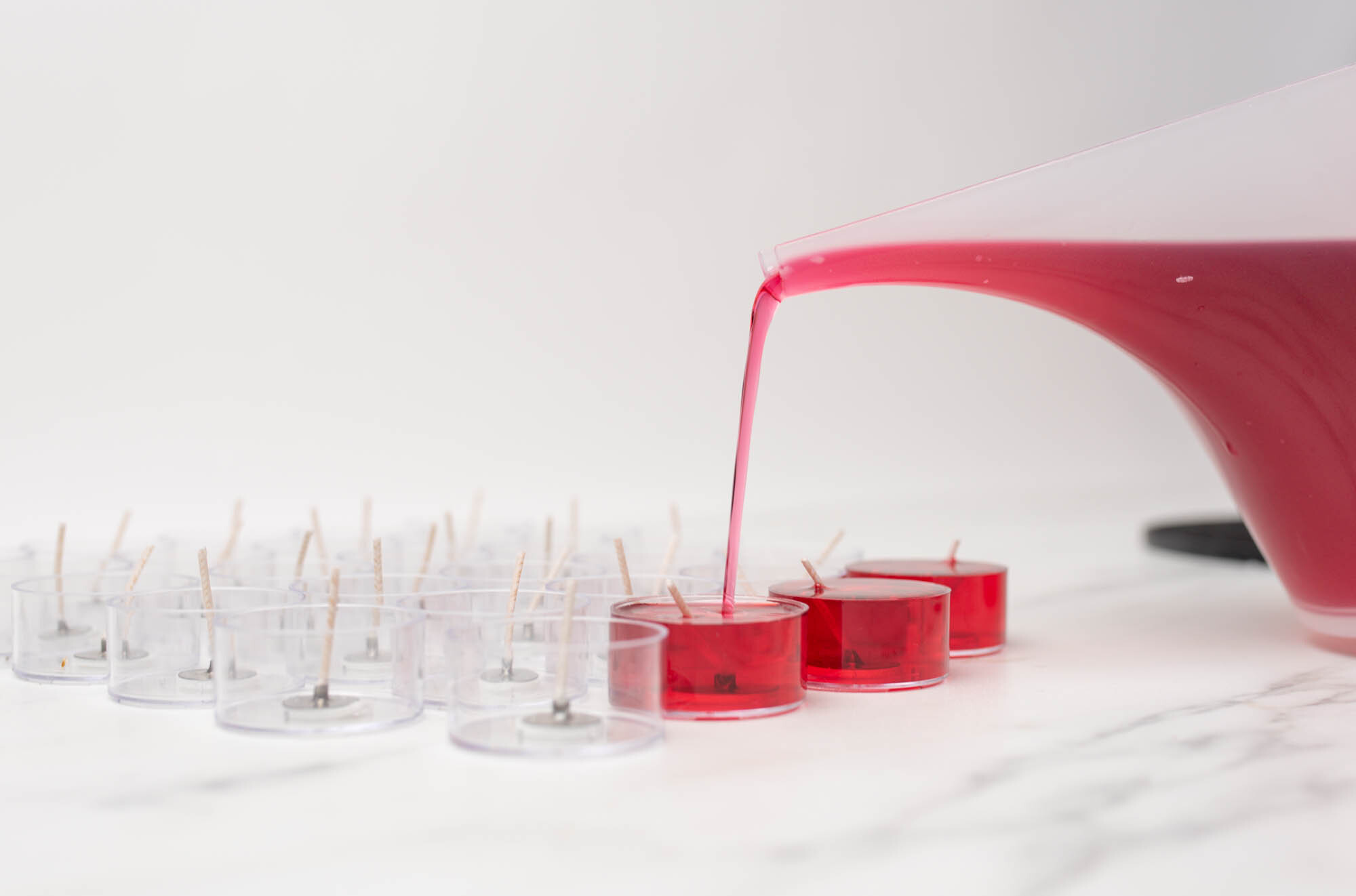 Pouring melted soy wax into tealight cups.