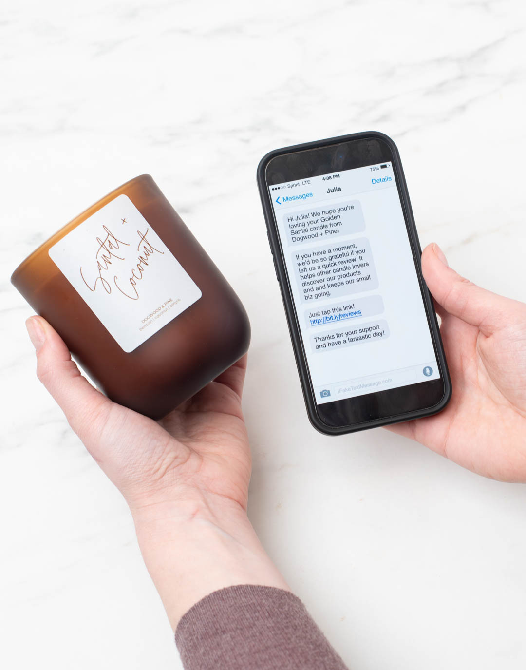 A pair of hands holds a candle in the left and a cell phone in the right