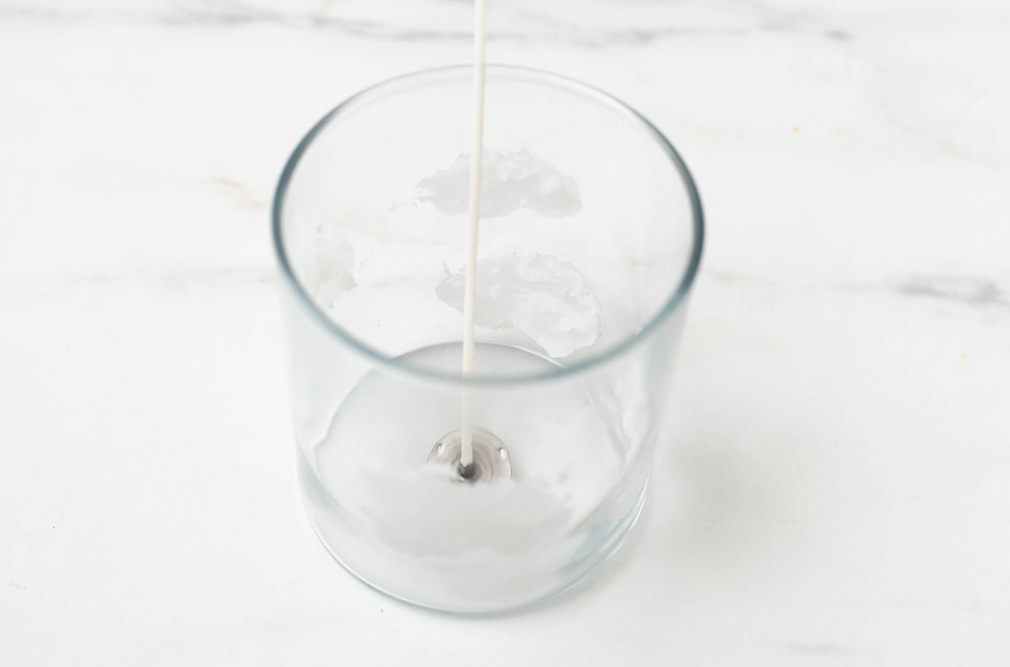 Clouds on the sides of a glass candle container created with wax.