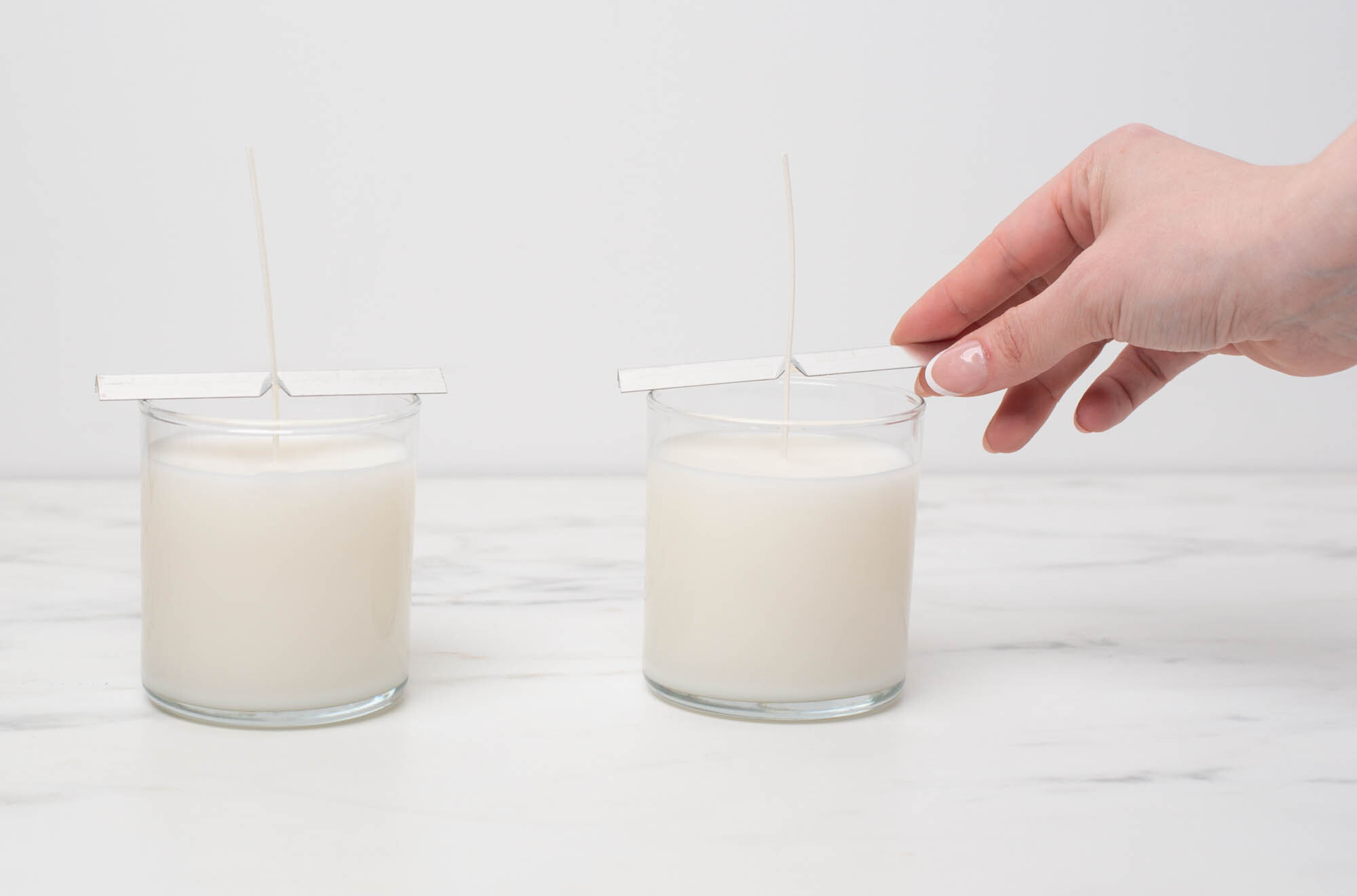 A hand ready to remove the wick bars of fully cooled candles.