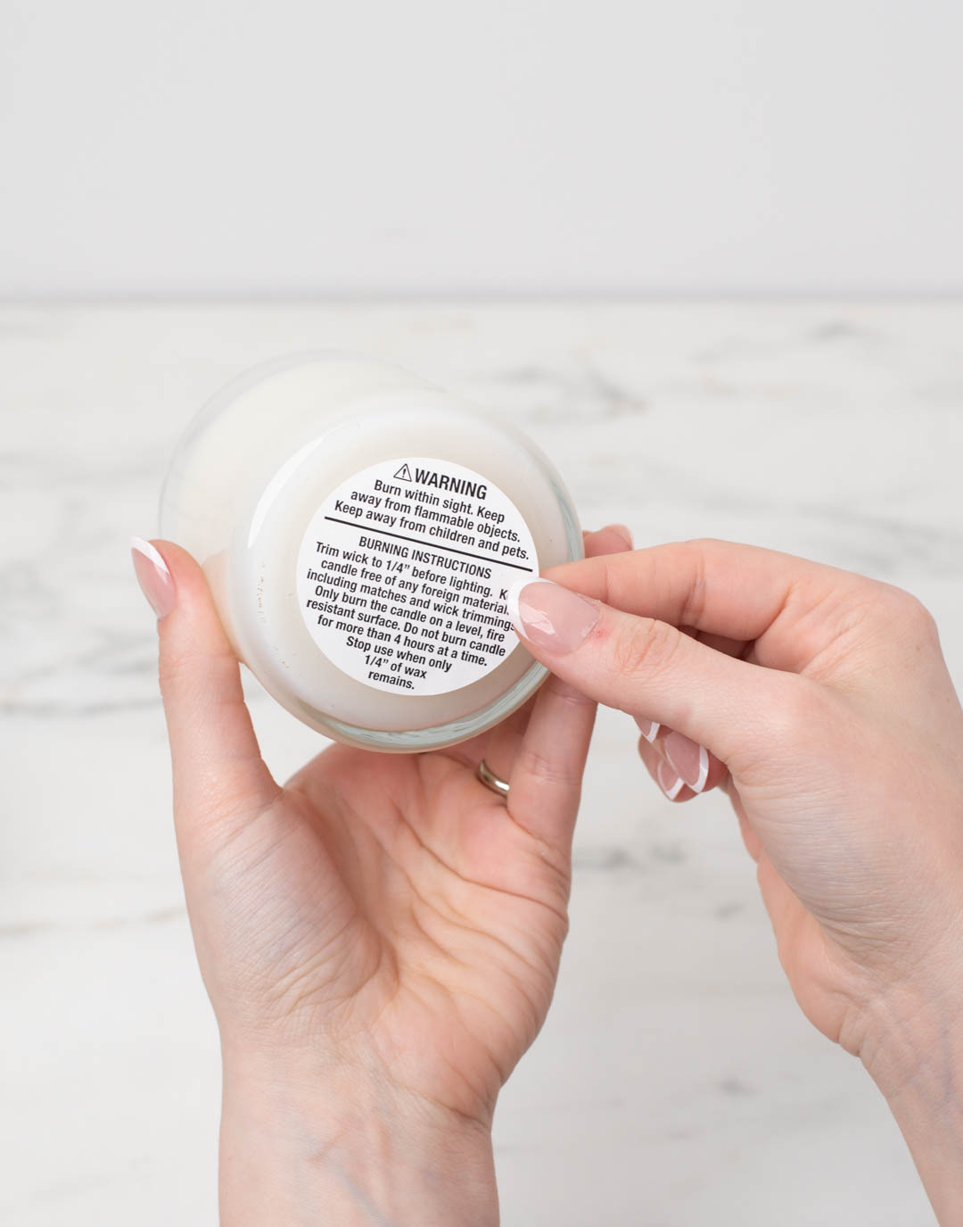 Hands placing a warning label on the bottom of a candle.