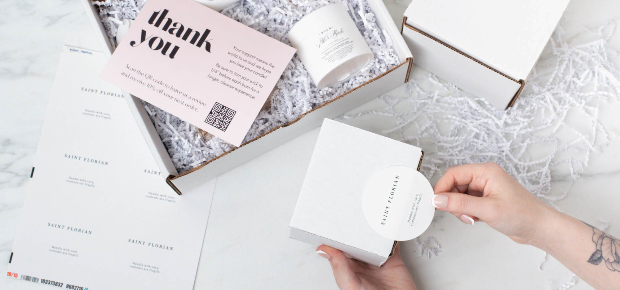 Light-skinned hands place a round label on a white box