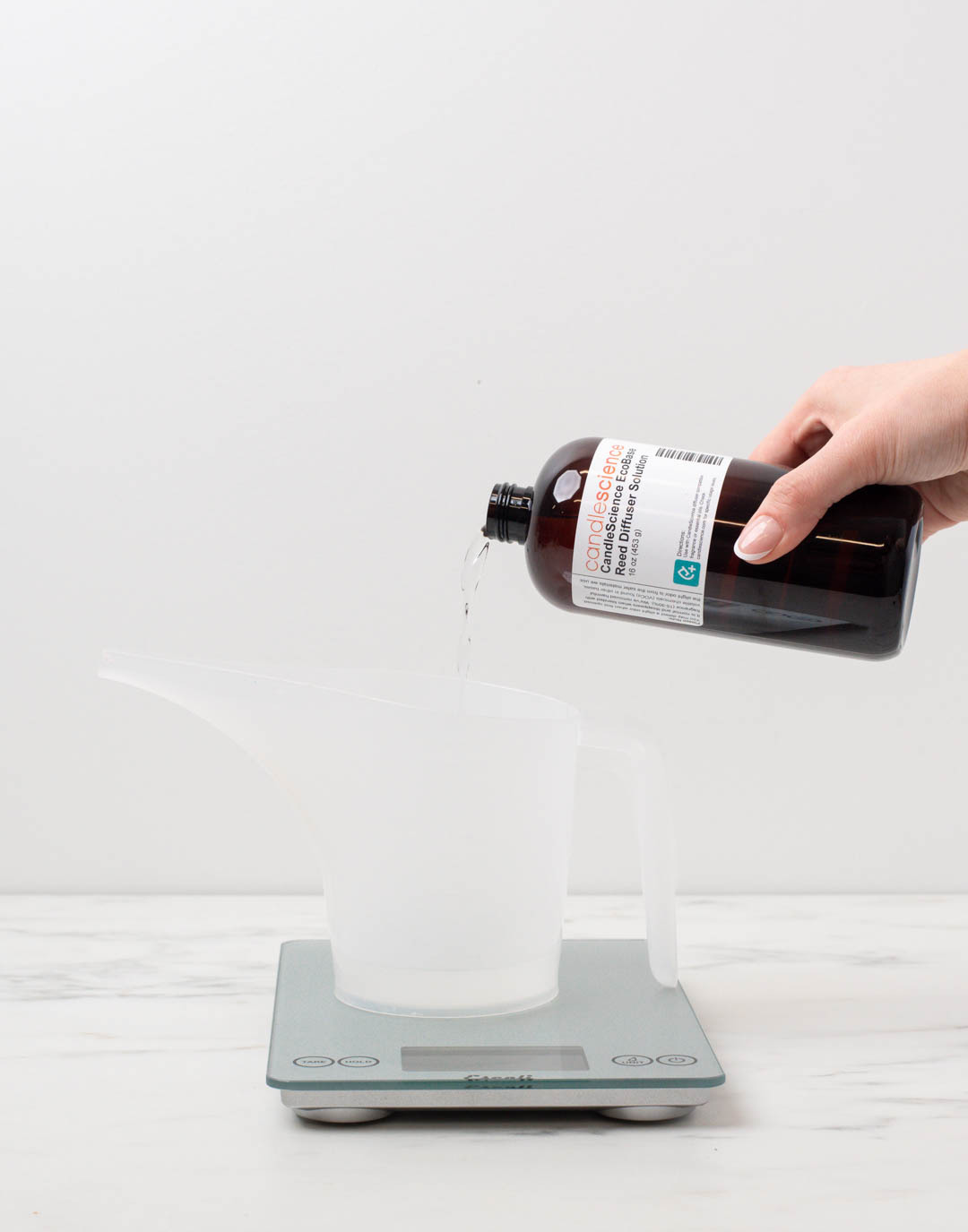 Pouring diffuser base into a funnel pouring pitcher on a scale.
