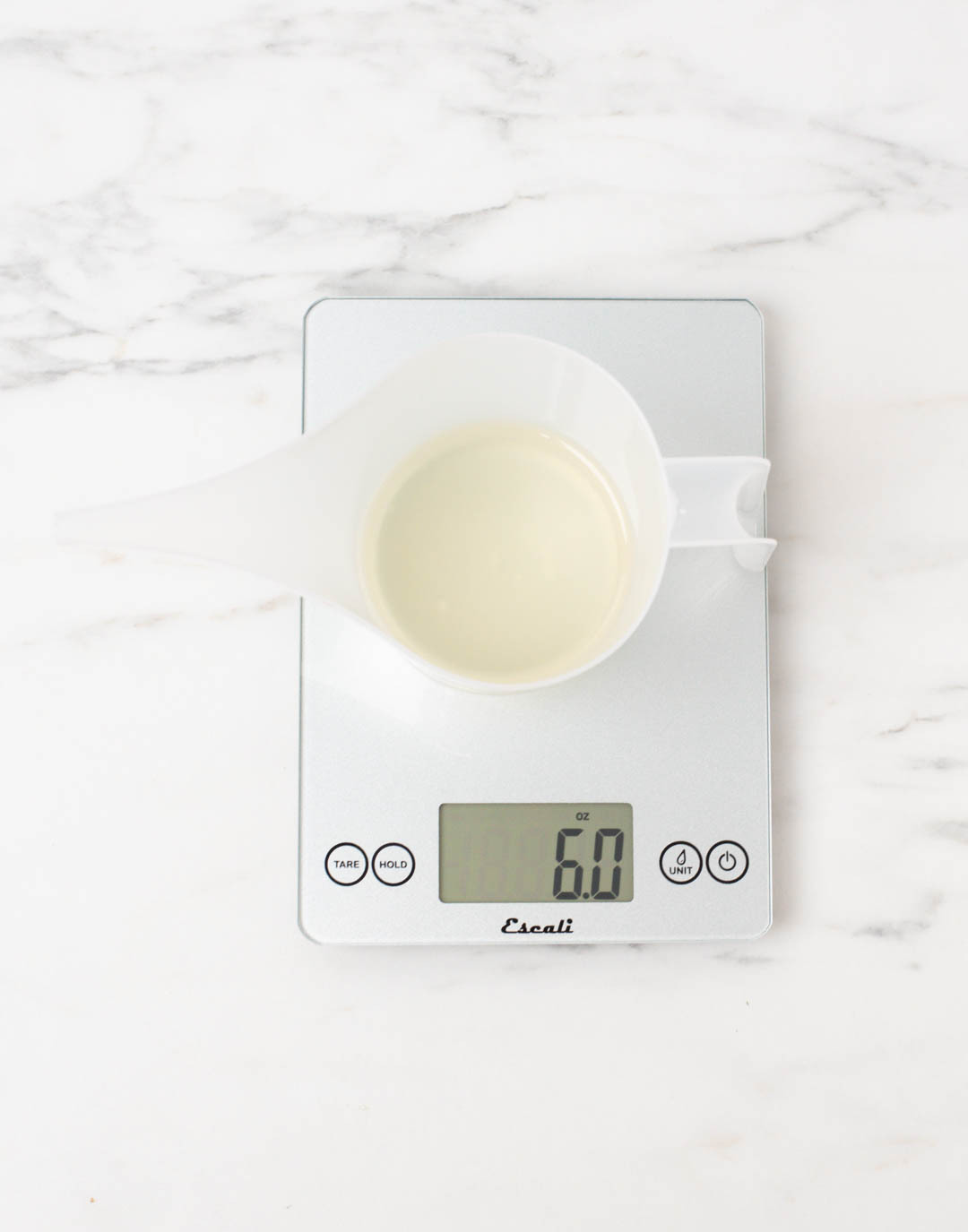 Diffuser base and fragrance mixture in a pouring pitcher on a scale reading 6 ounces.