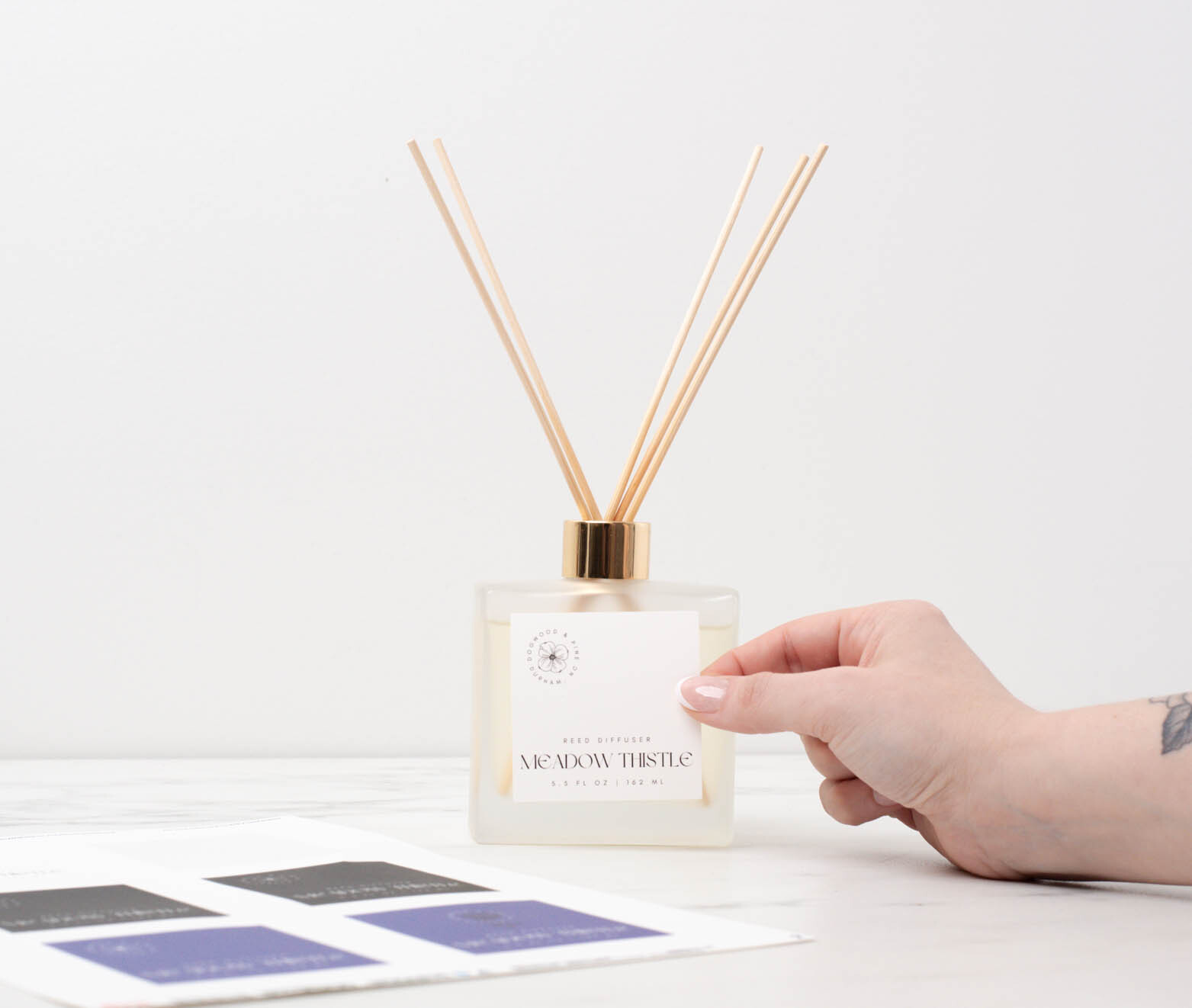 Placing a decorative label on the front of a finished reed diffuser.