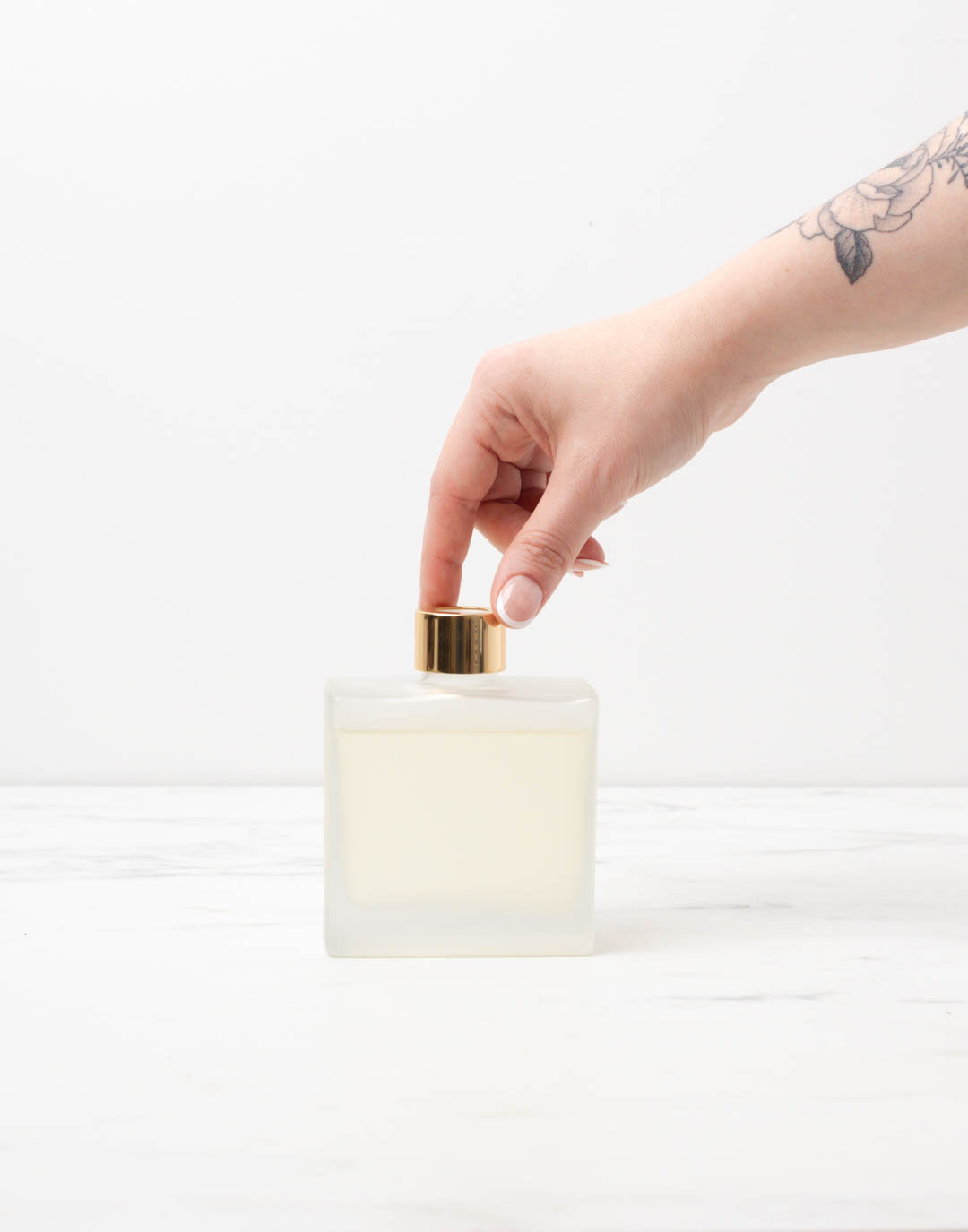 Hand twisting gold collar onto diffuser bottle.