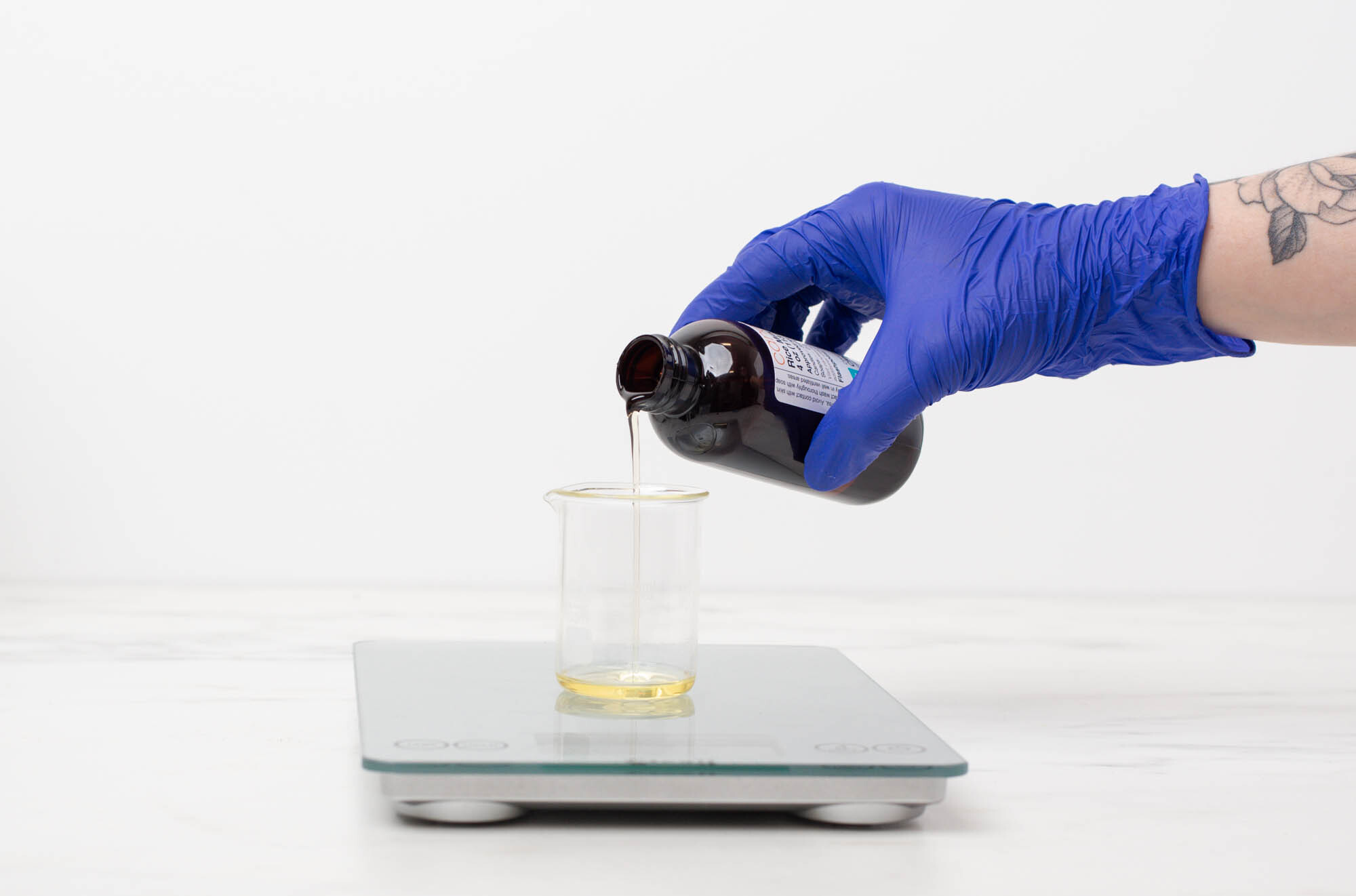 Pouring fragrance into a pouring pitcher with diffuser base in it on a scale.