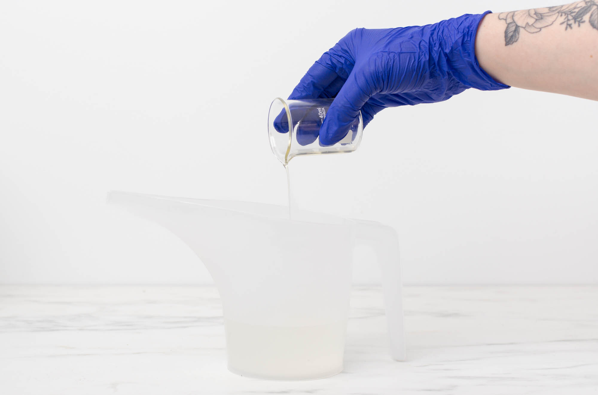 Pouring mixture from pouring pitcher into reed diffuser bottle.