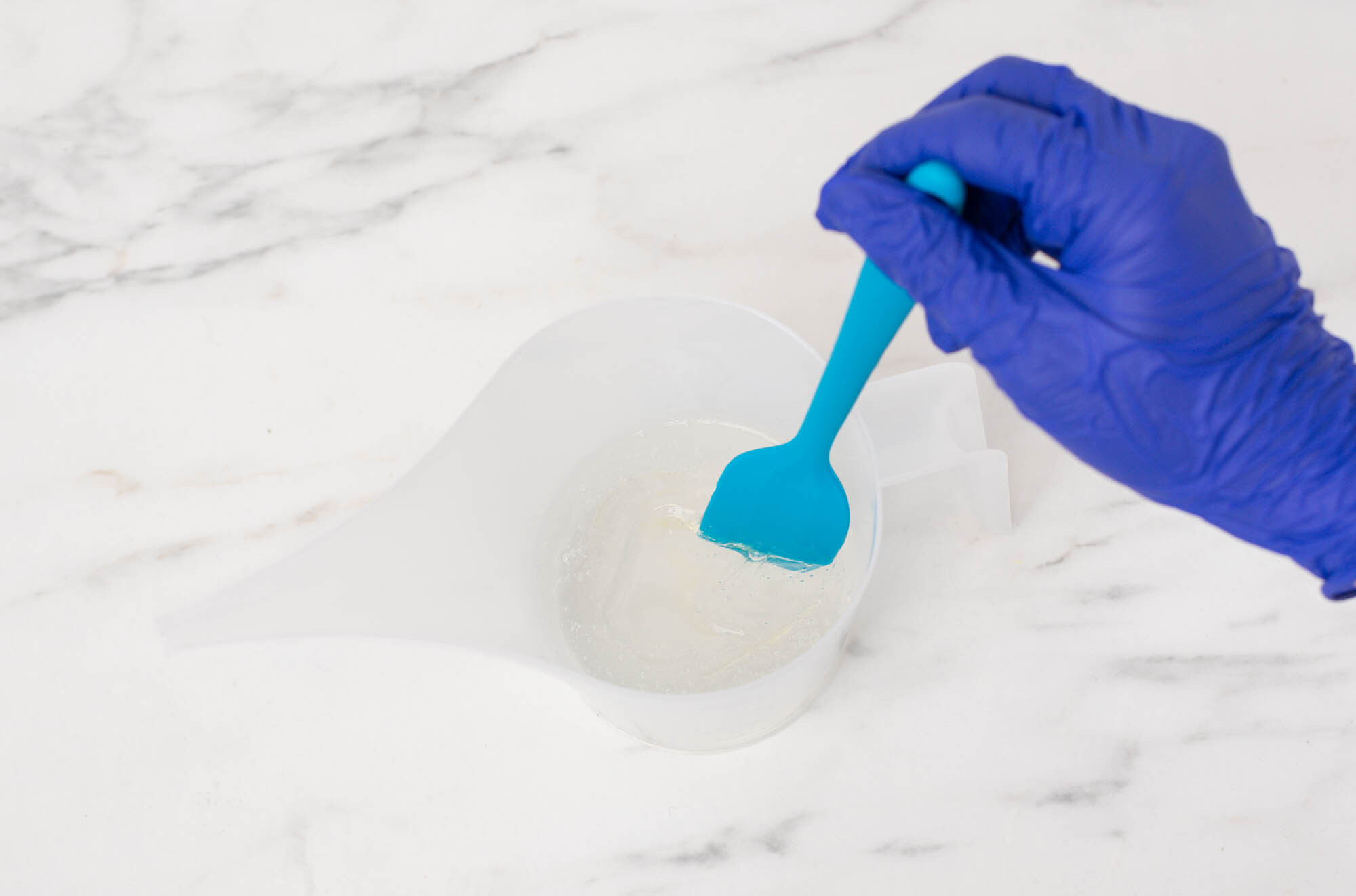 Pouring mixture into diffuser bottle using a silver funnel.