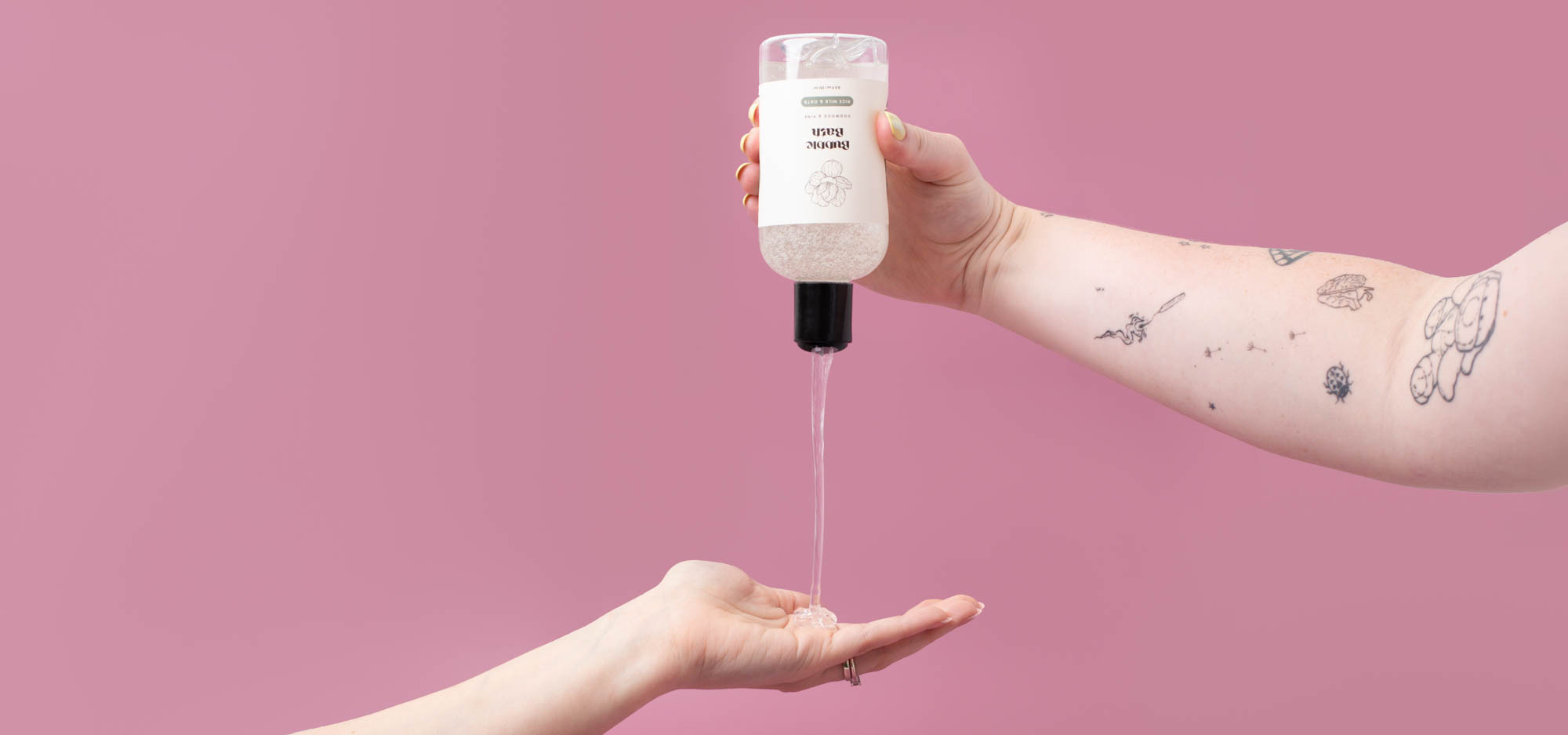 Hands squeezing a bottle of bubble bath for a DIY tutorial.