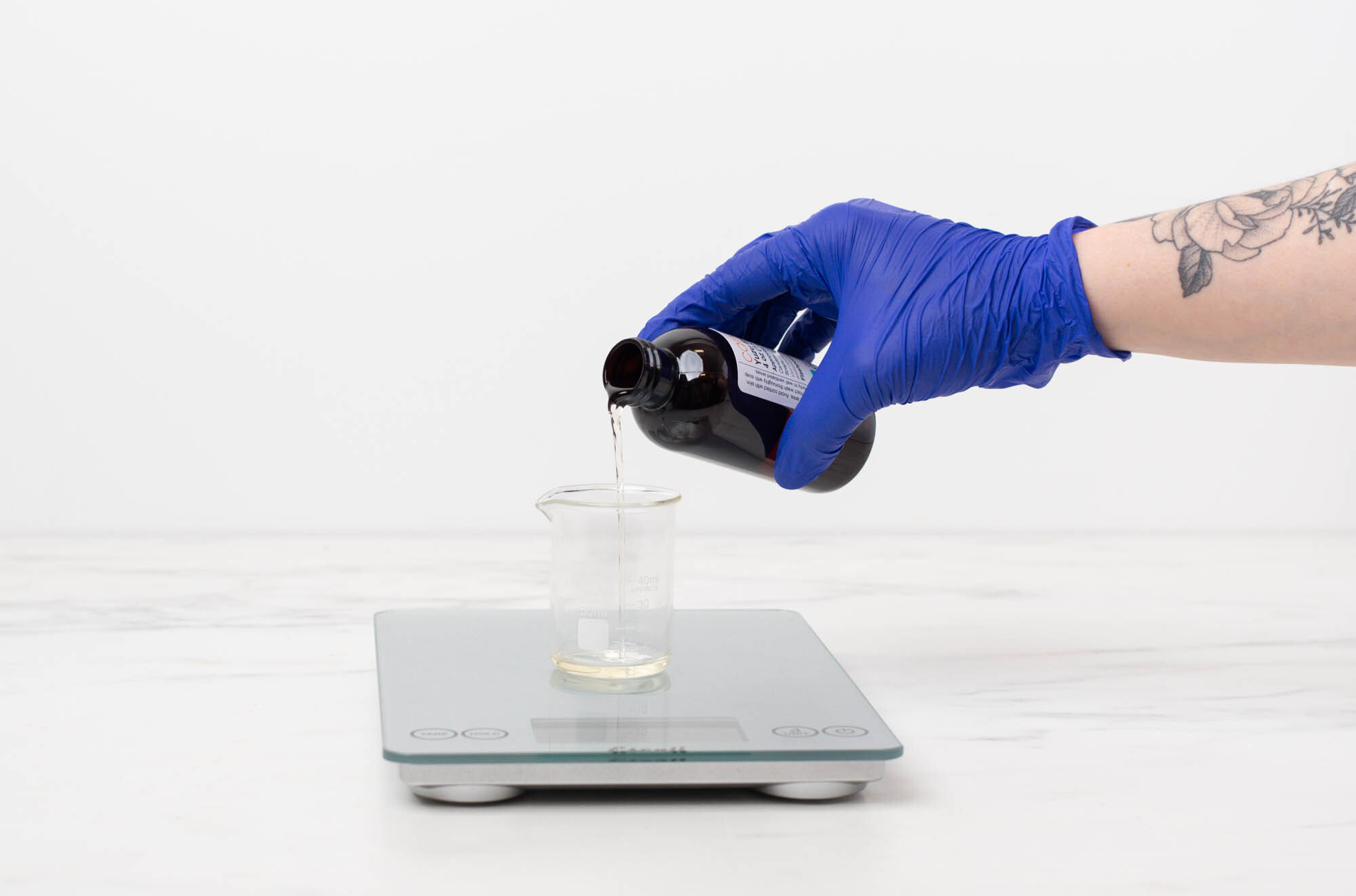 Pouring fragrance into a pouring pitcher with diffuser base in it on a scale. 