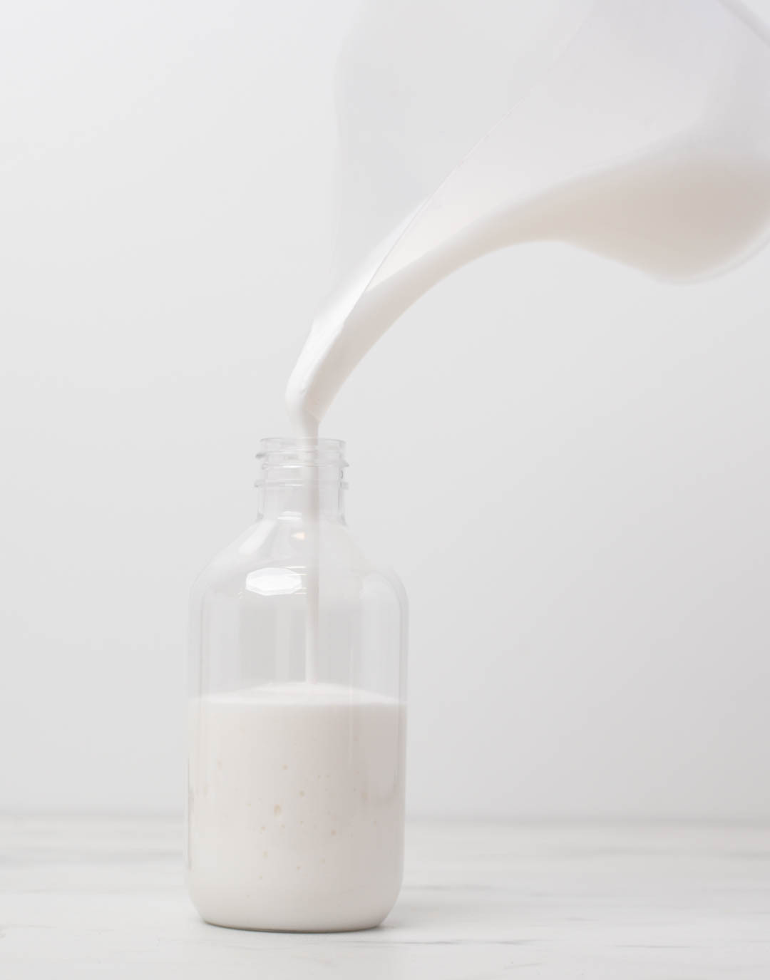 Hand placing clear stopper into neck of reed diffuser bottle.