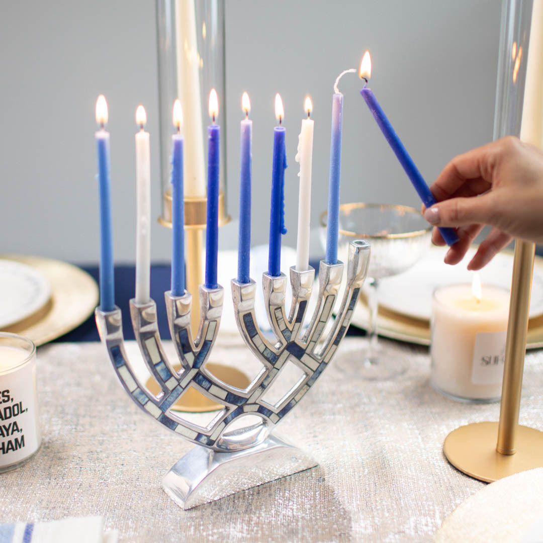 Hanukkah table setting with a lit menorah.