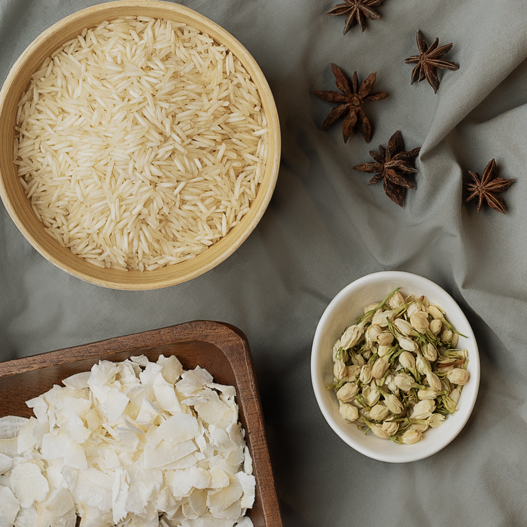 Top down view of rice, cardamom, and star anise on gray fabric.