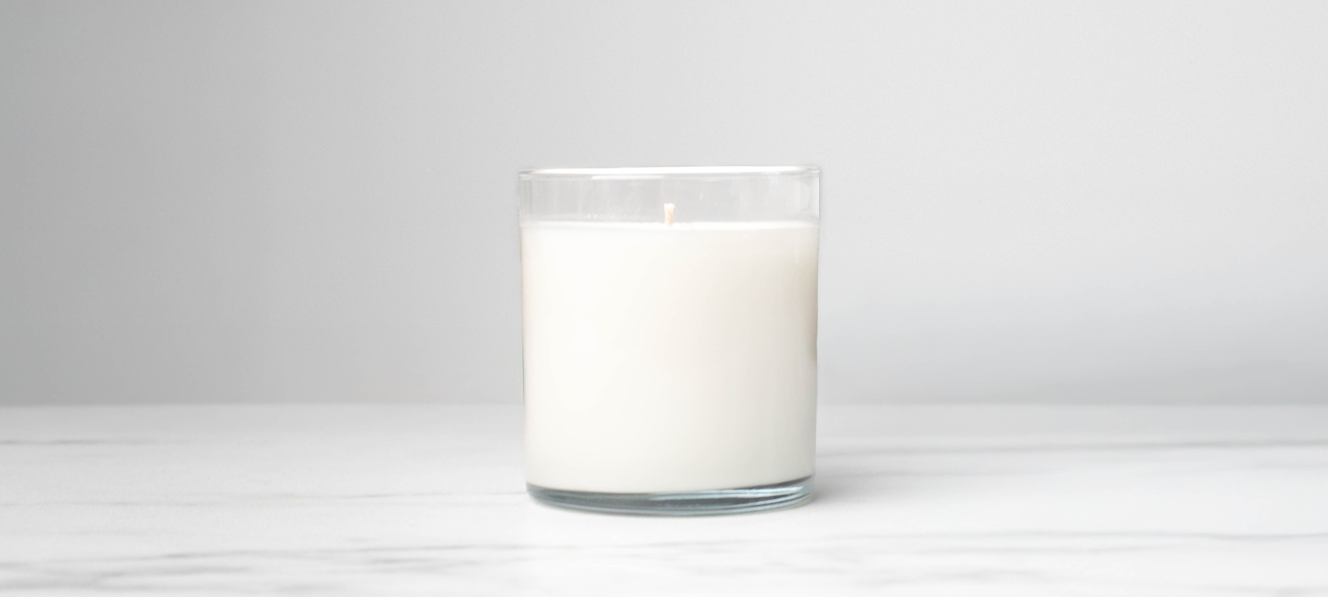A clear straight sided tumbler jar using CandleScience Coconut Apricot Wax dyed blue showing a wet spot on the side.