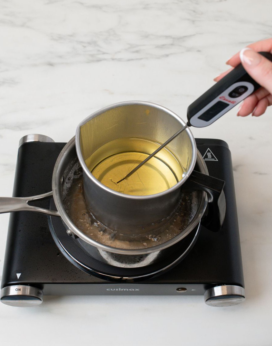 Checking the temperature of melted beeswax.