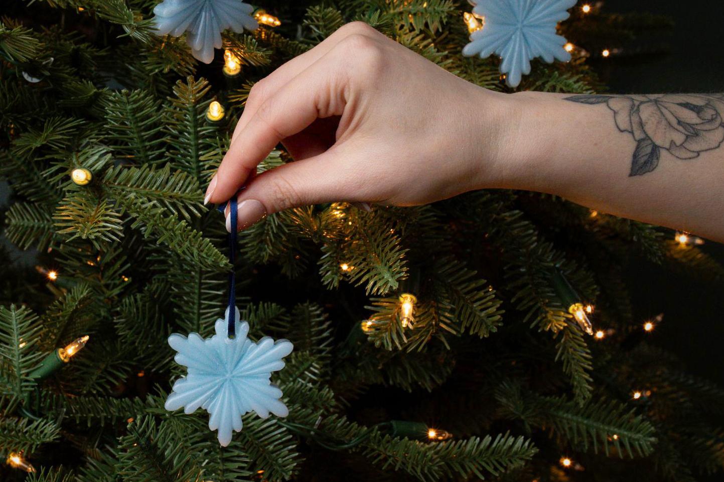 Beeswax Christmas tree star ornament hanging on a pine tree branch.