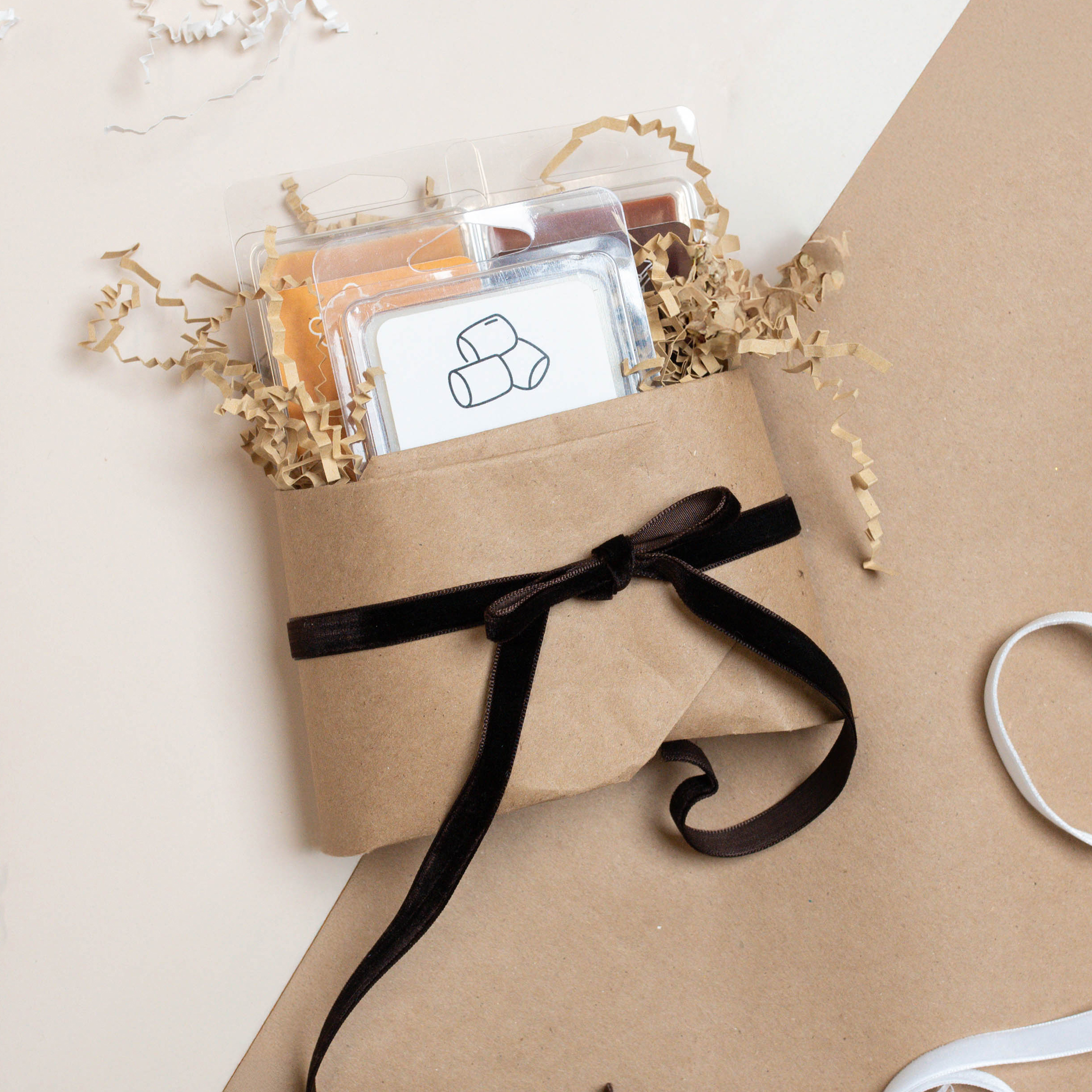 Three s'mores scented wax melts wrapped in brown paper with a ribbon.