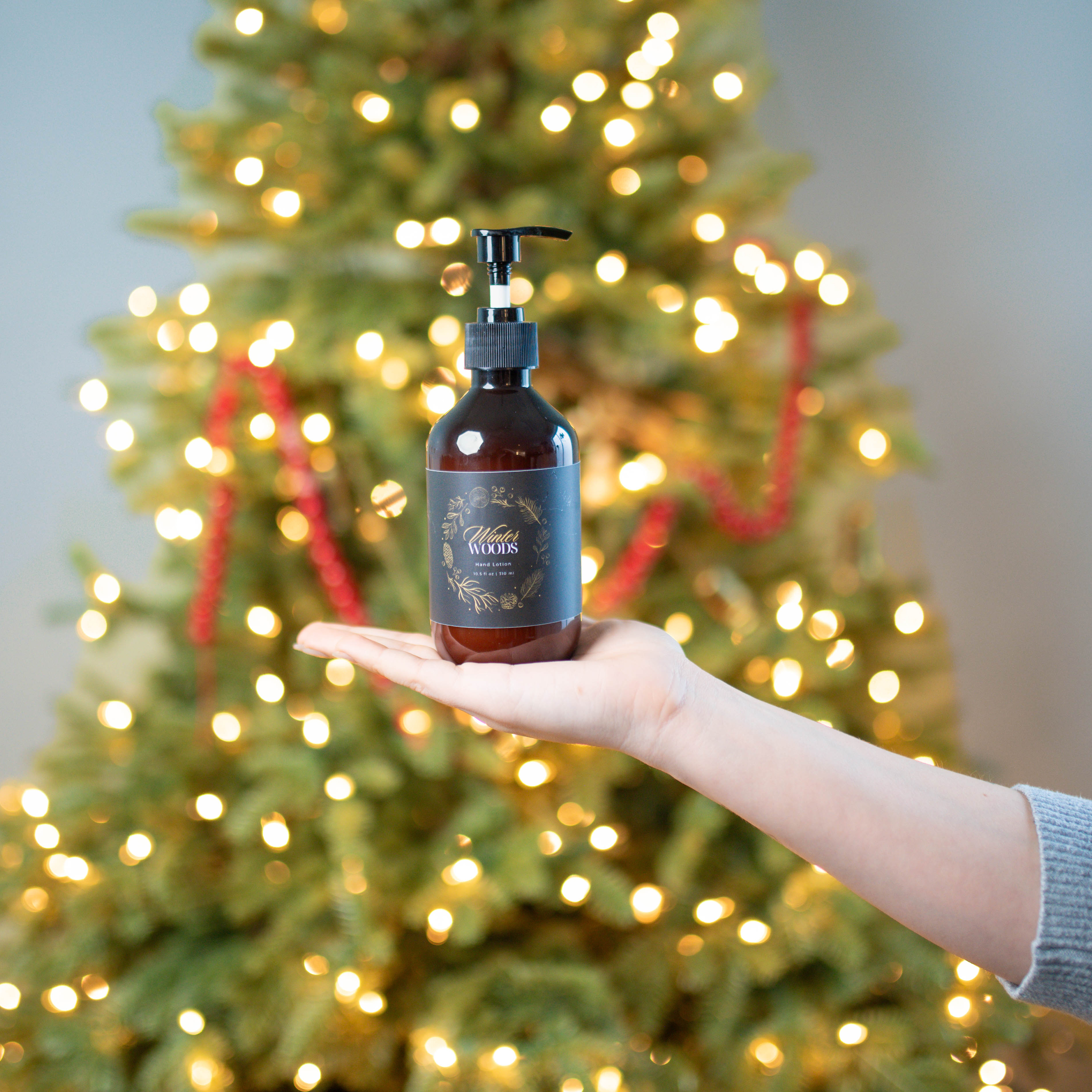 Hand lotion in front of a lit christmas tree.