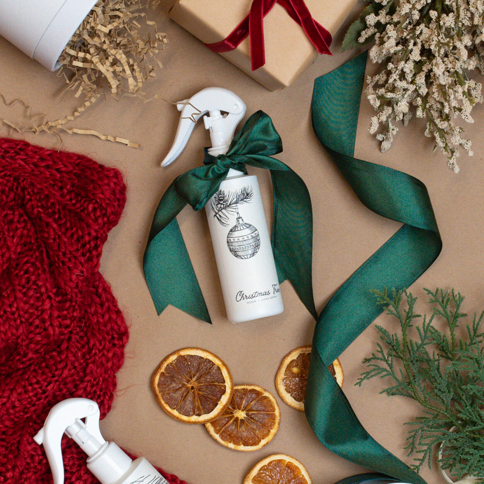 Top down view of gift wrapping a bottle of room and linen spray with ribbon.