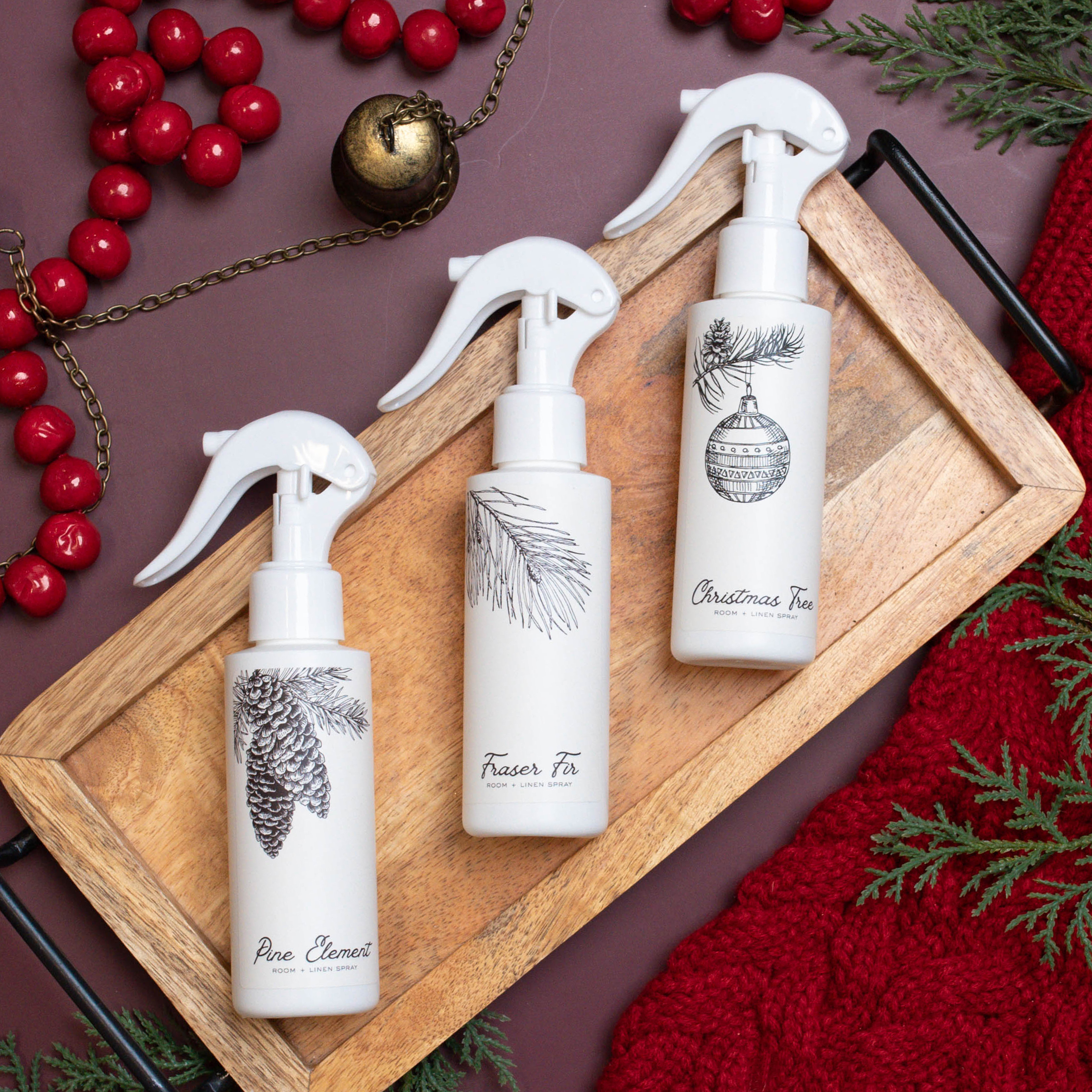 Top down view of three bottles of room and linen spray on a gold plate with decorations. 
