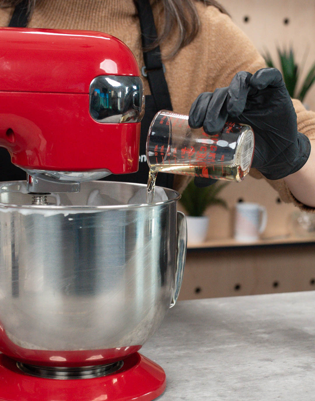 CandleScience fragrance oil being poured from a beaker into a batch of lotion base