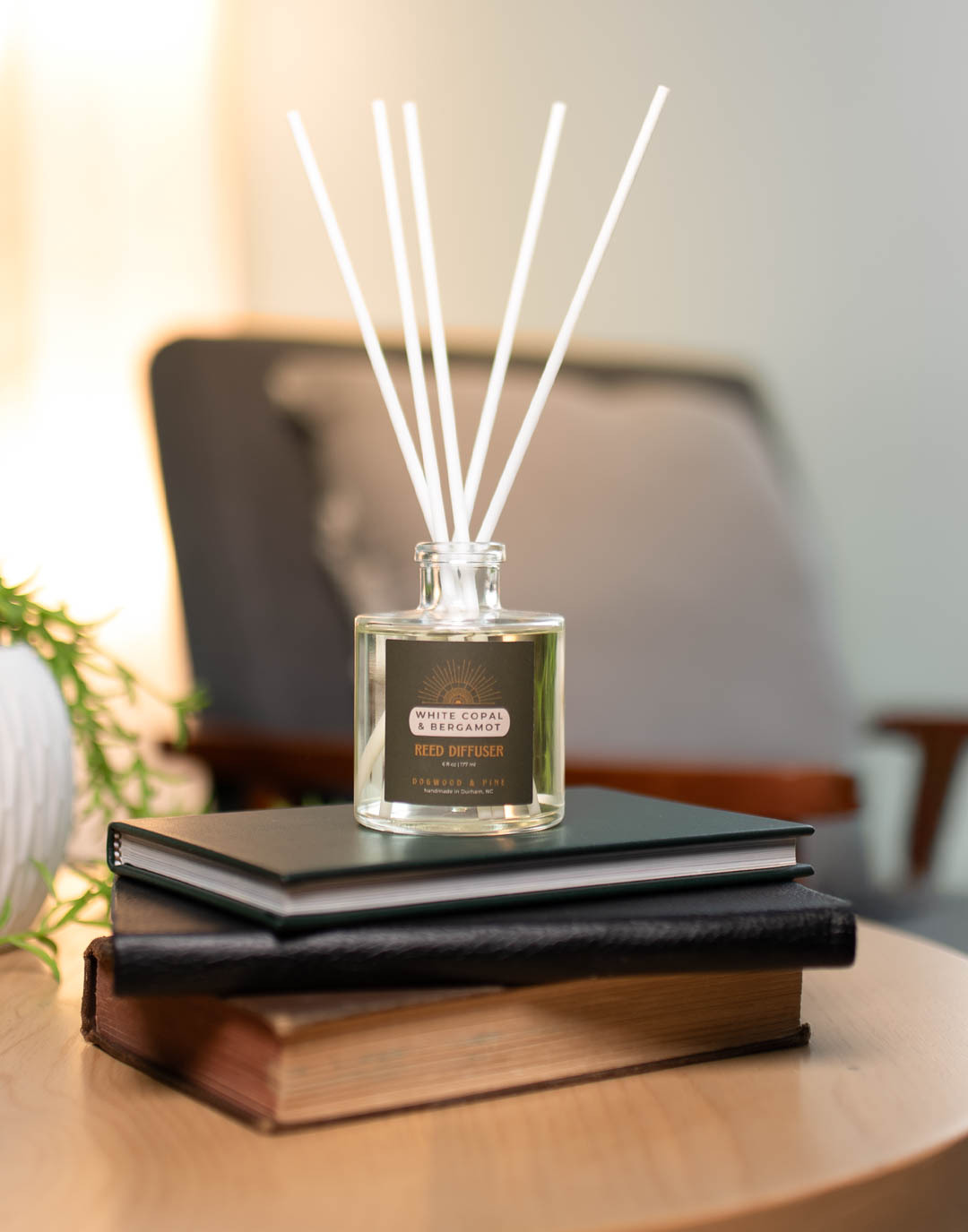 A reed diffuser made from CandleScience supplies sits on a stack of books
