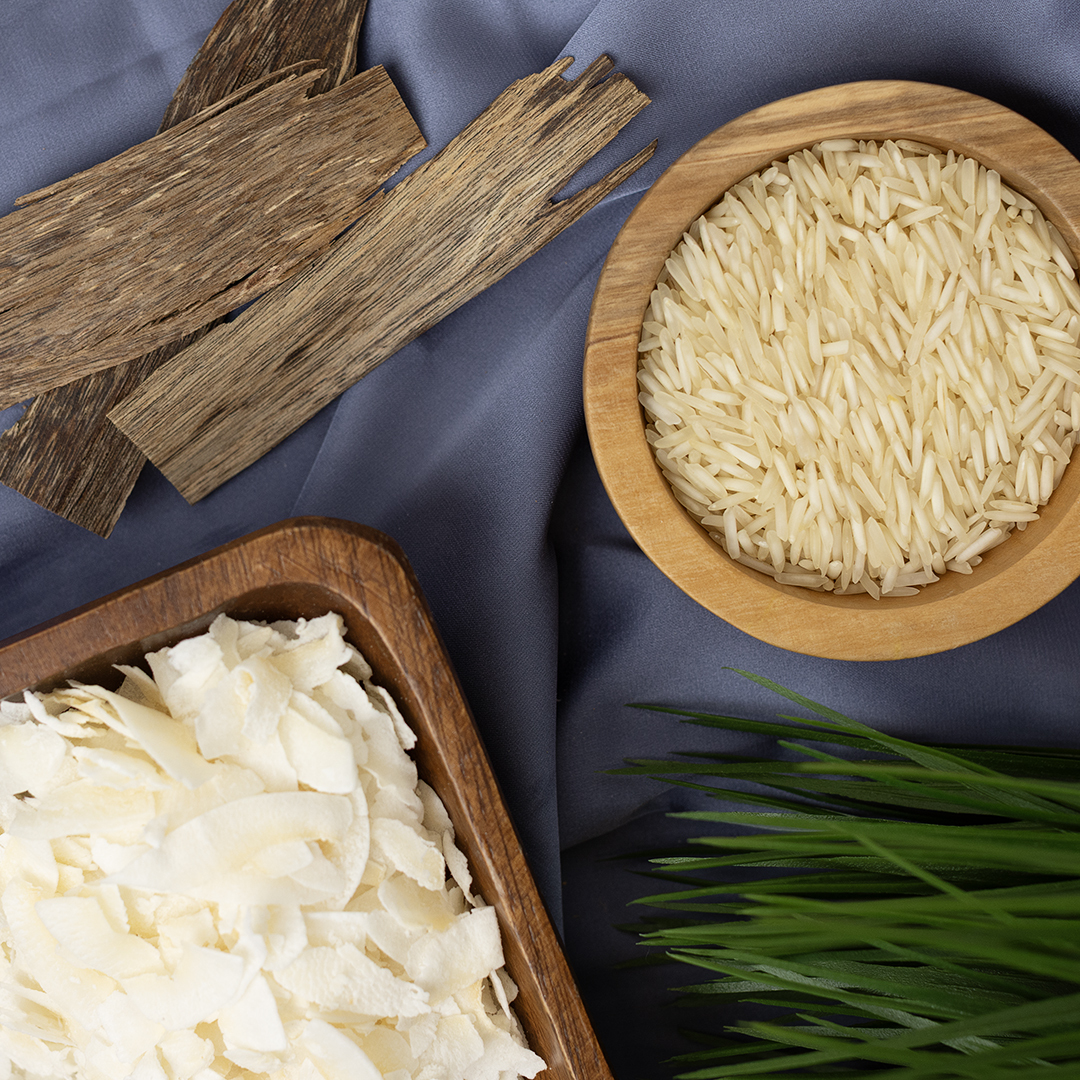 Top down view of rice, cardamom, and star anise on gray fabric.