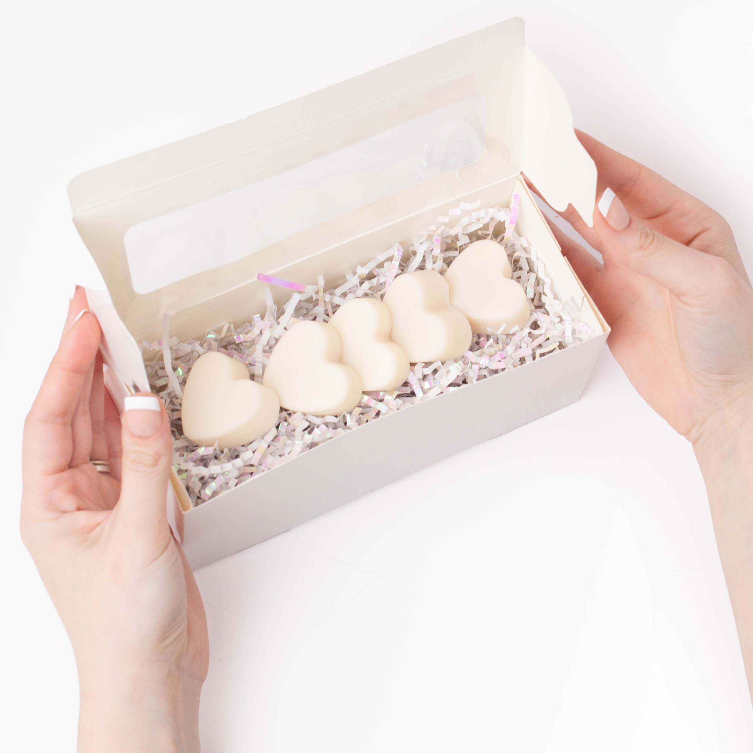 Two hands arranging bleeding heart wax melts in a white gift box