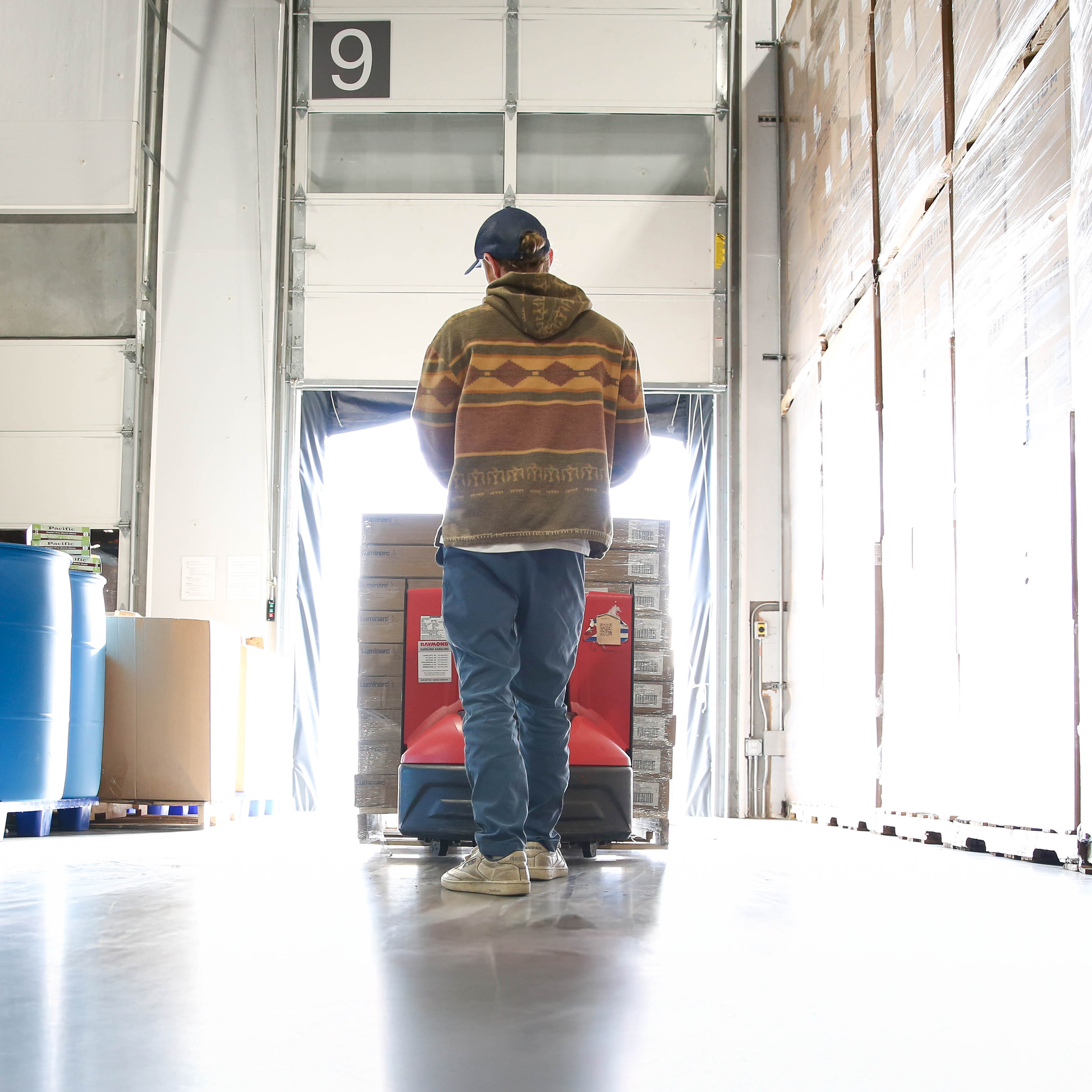 Pushing a pallet of boxes in a warehouse to loading dock.