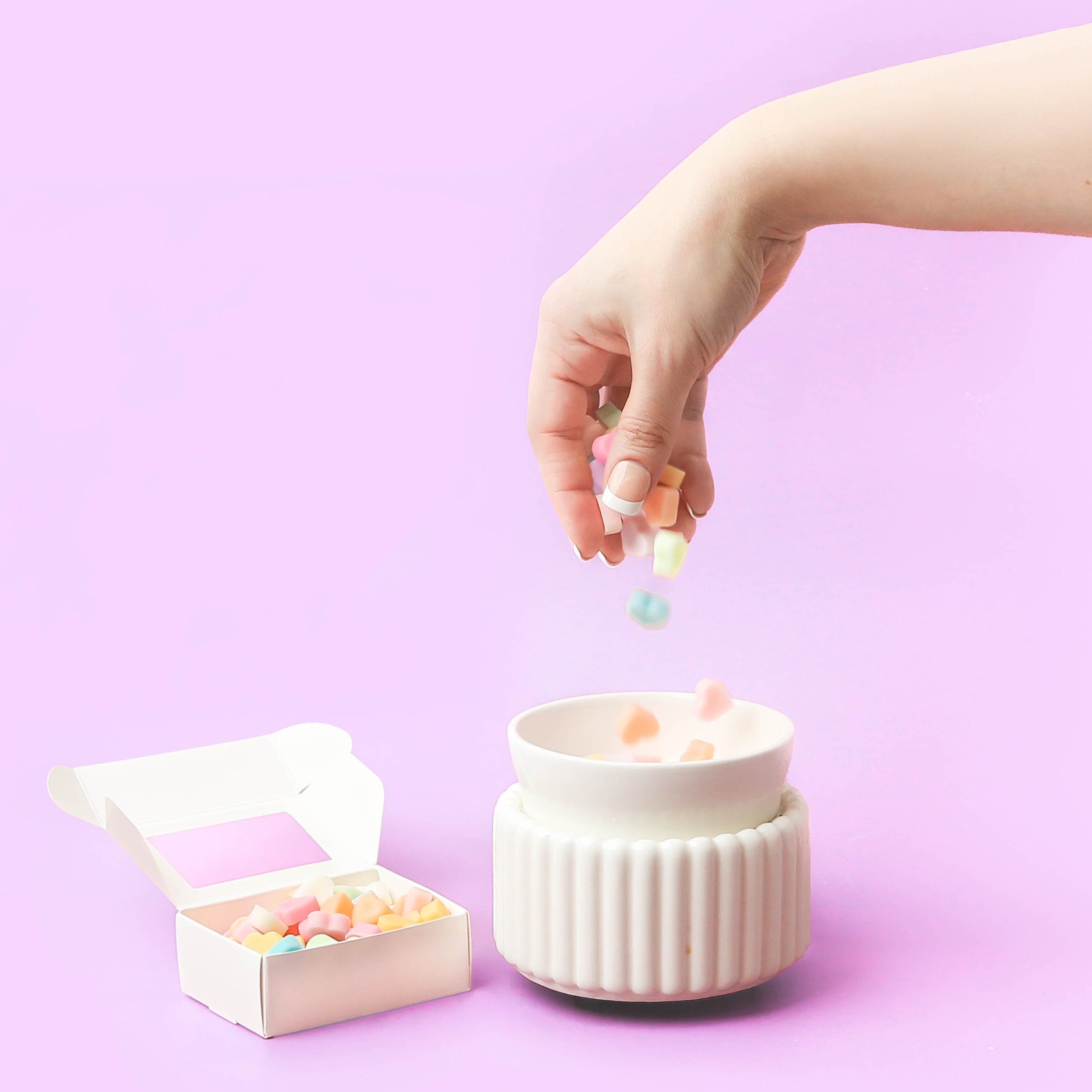 Multi-colored Candy heart wax melts being dropped into a wax warmer