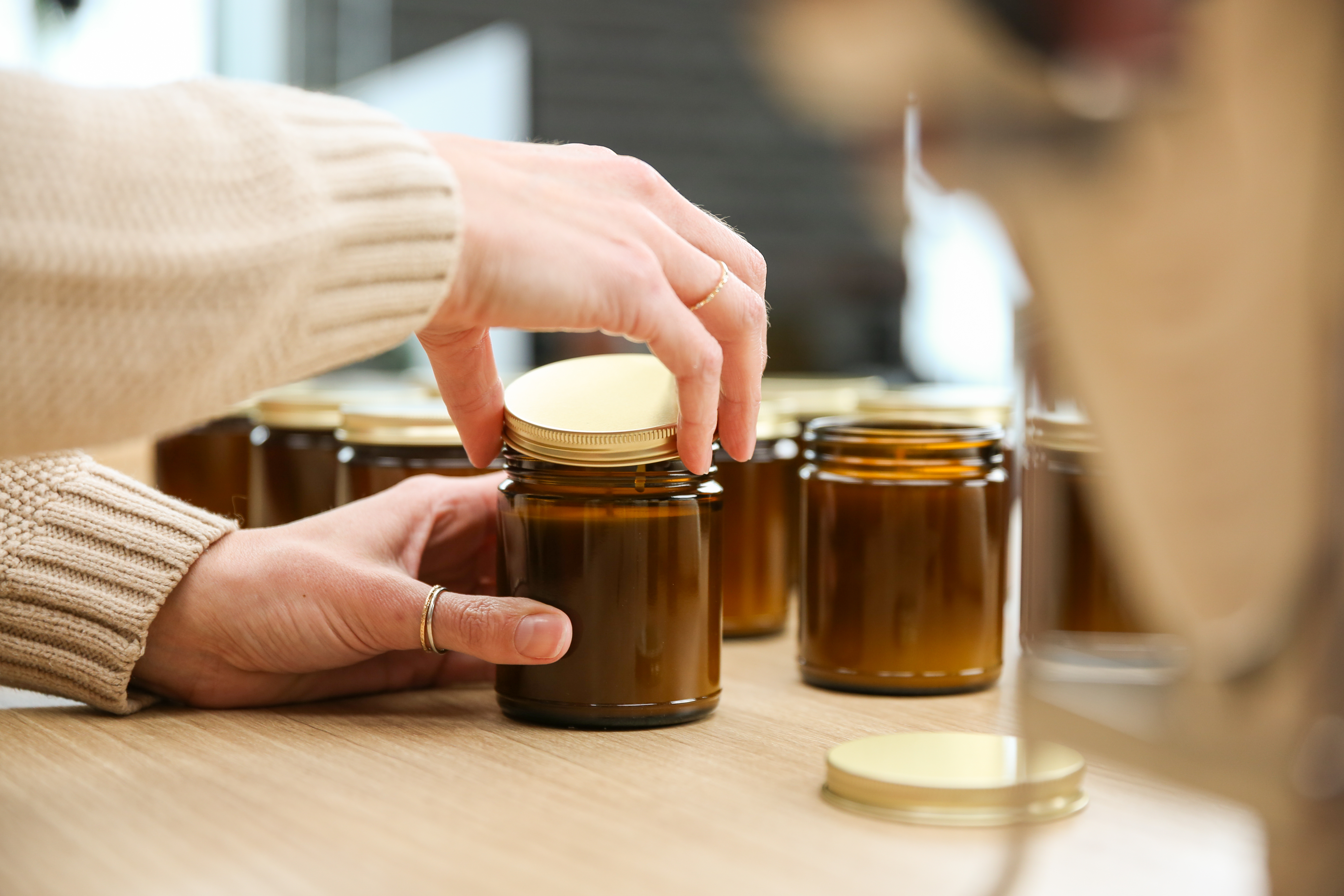 Light-skinned hands putting a lid on a candle jar